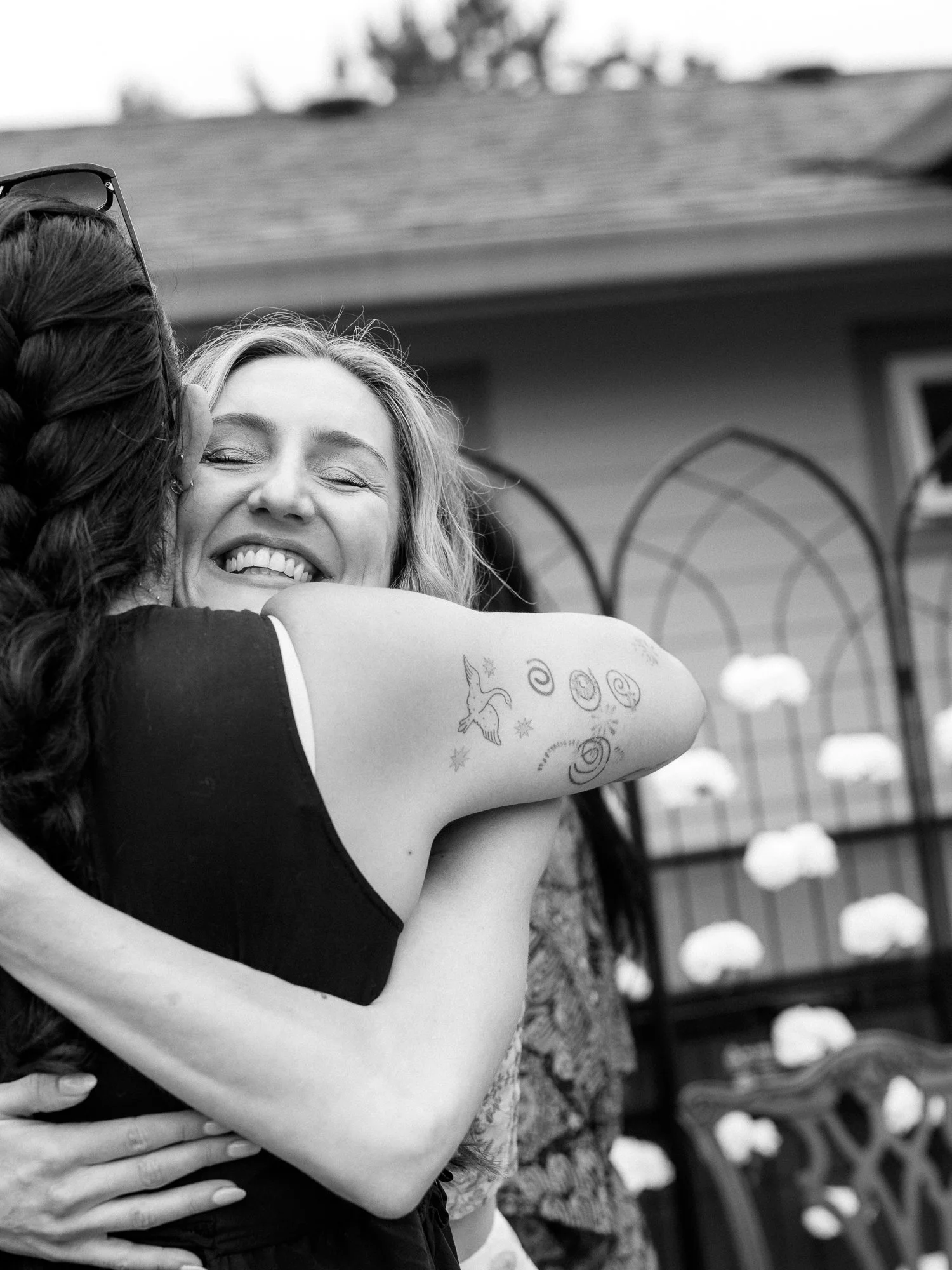 Black-and-white candid of Alacia hugging a guest during the outdoor Haldi celebration.