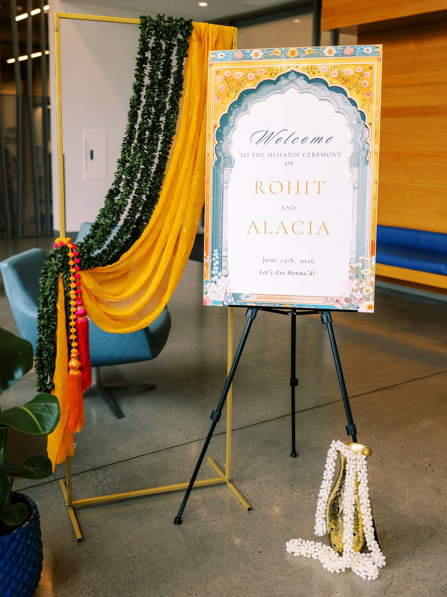 Welcome sign for Rohit and Alacia’s Mehndi ceremony decorated with yellow draping, greenery, and floral details.