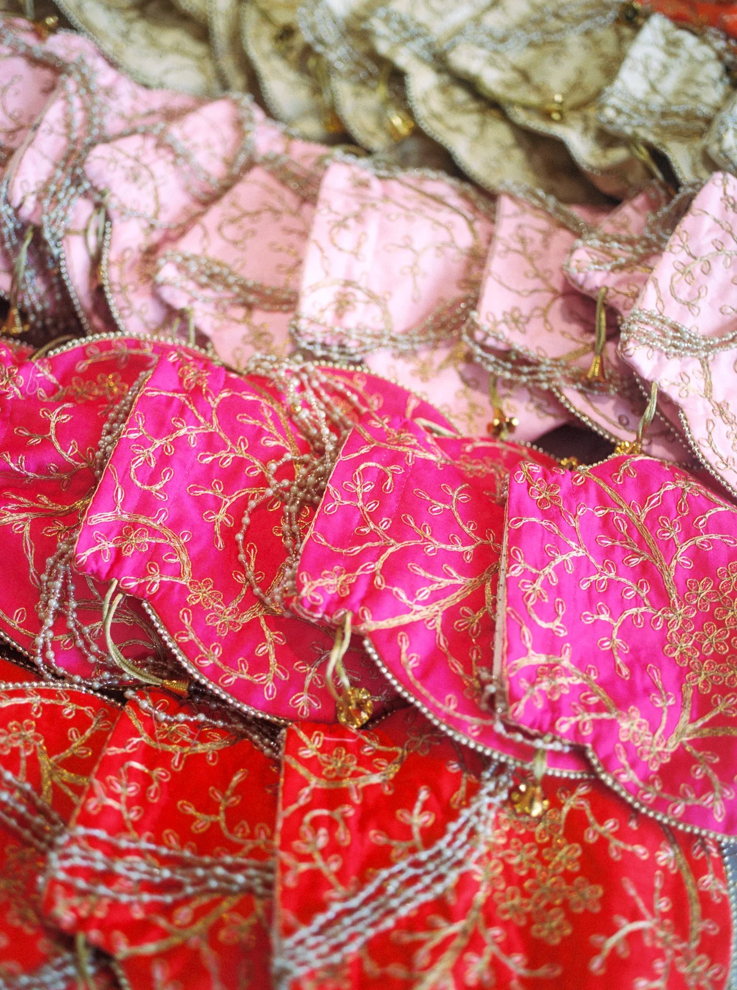 Colorful embroidered fabric in pink, red, and gold prepared as part of the Mehndi celebration decor.