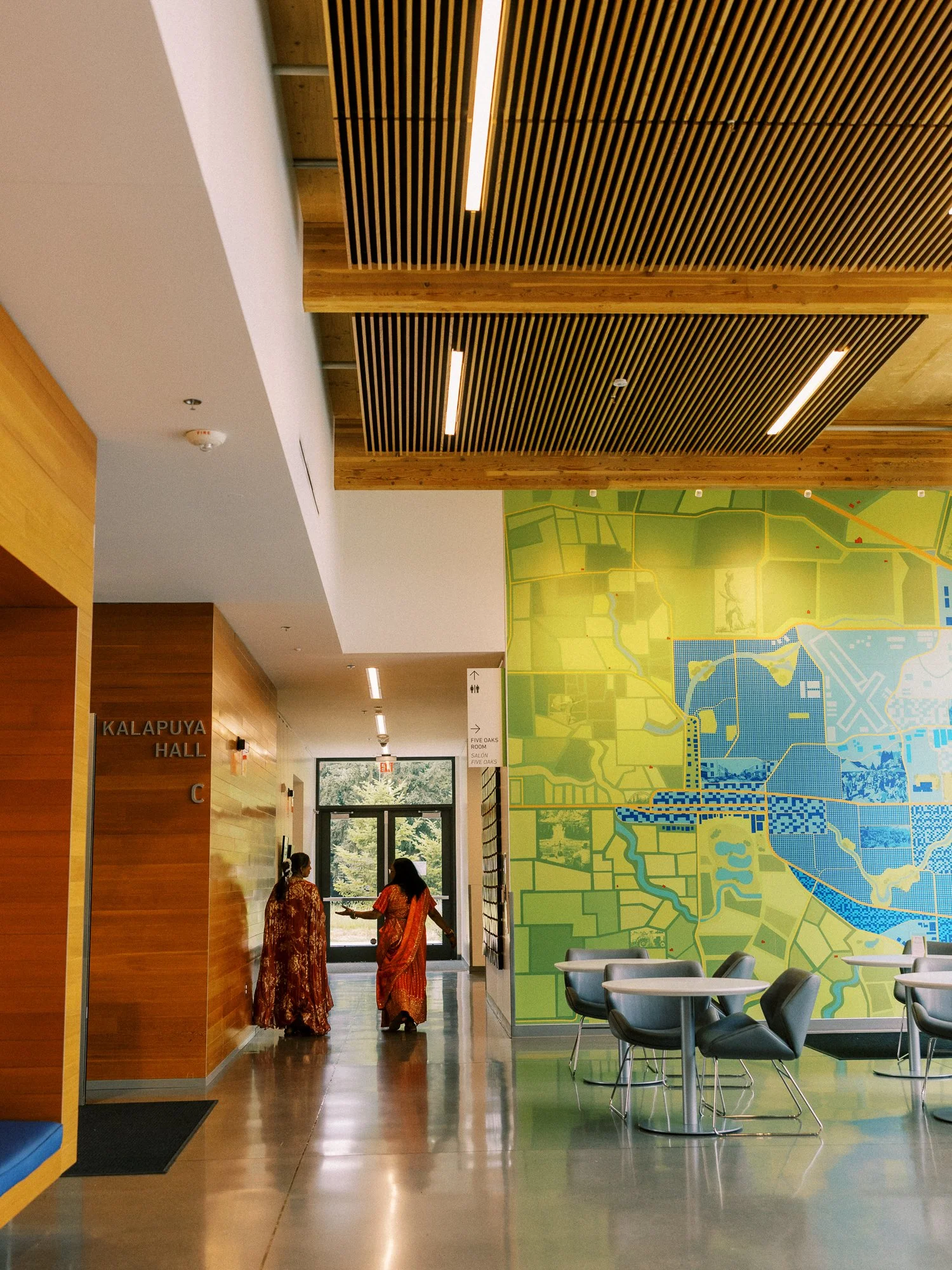 Two guests walking through the venue beside a large green and blue wall mural.