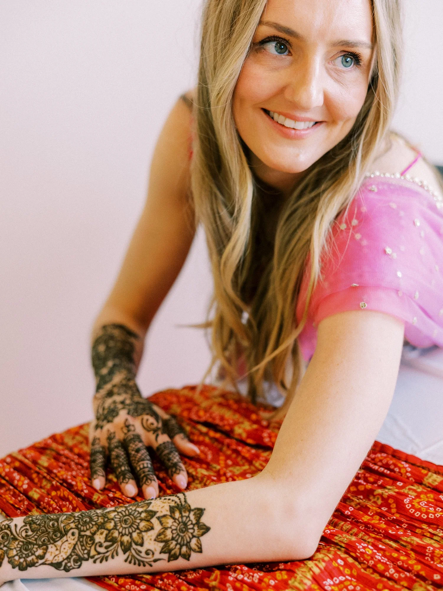 Alacia displaying fresh henna designs on her hands and arms while wearing a bright pink outfit.