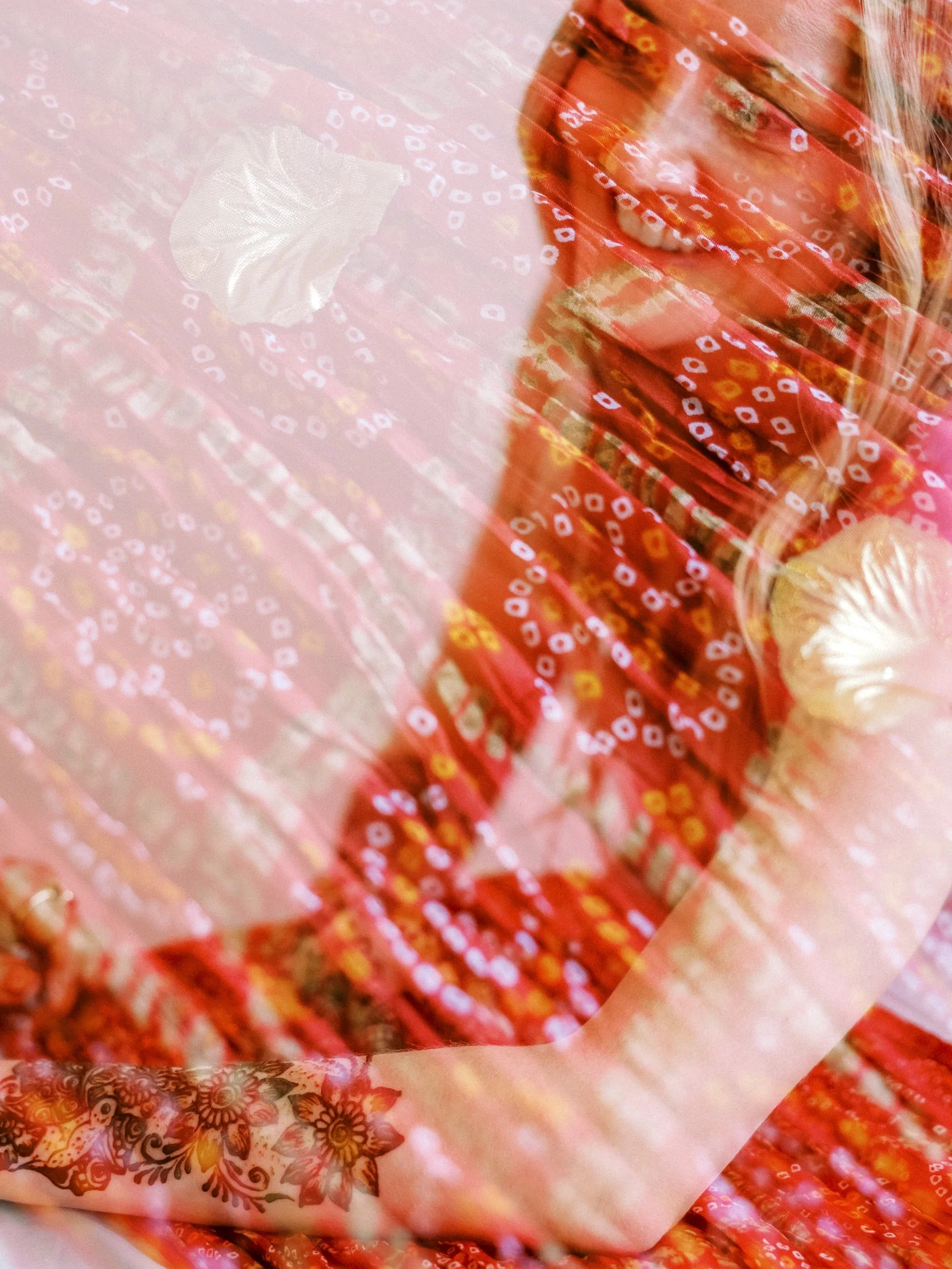 Artistic double-exposure portrait of Alacia showing her henna against red and pink patterned fabric.