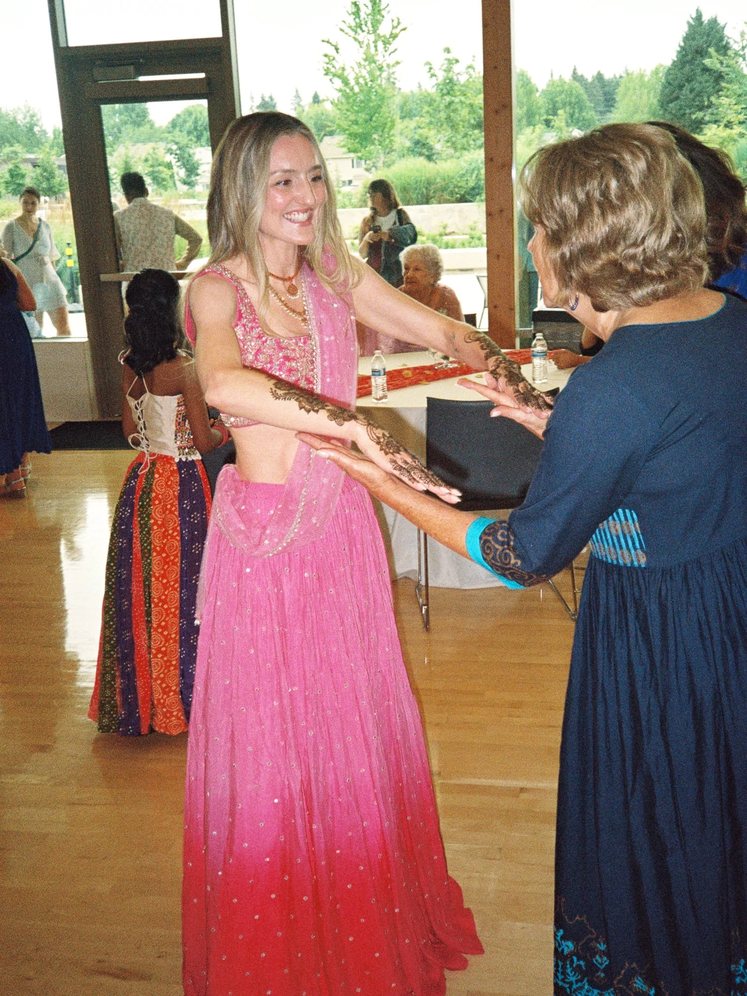 Alacia greeting a guest while showing the detailed henna covering her hands and forearms.