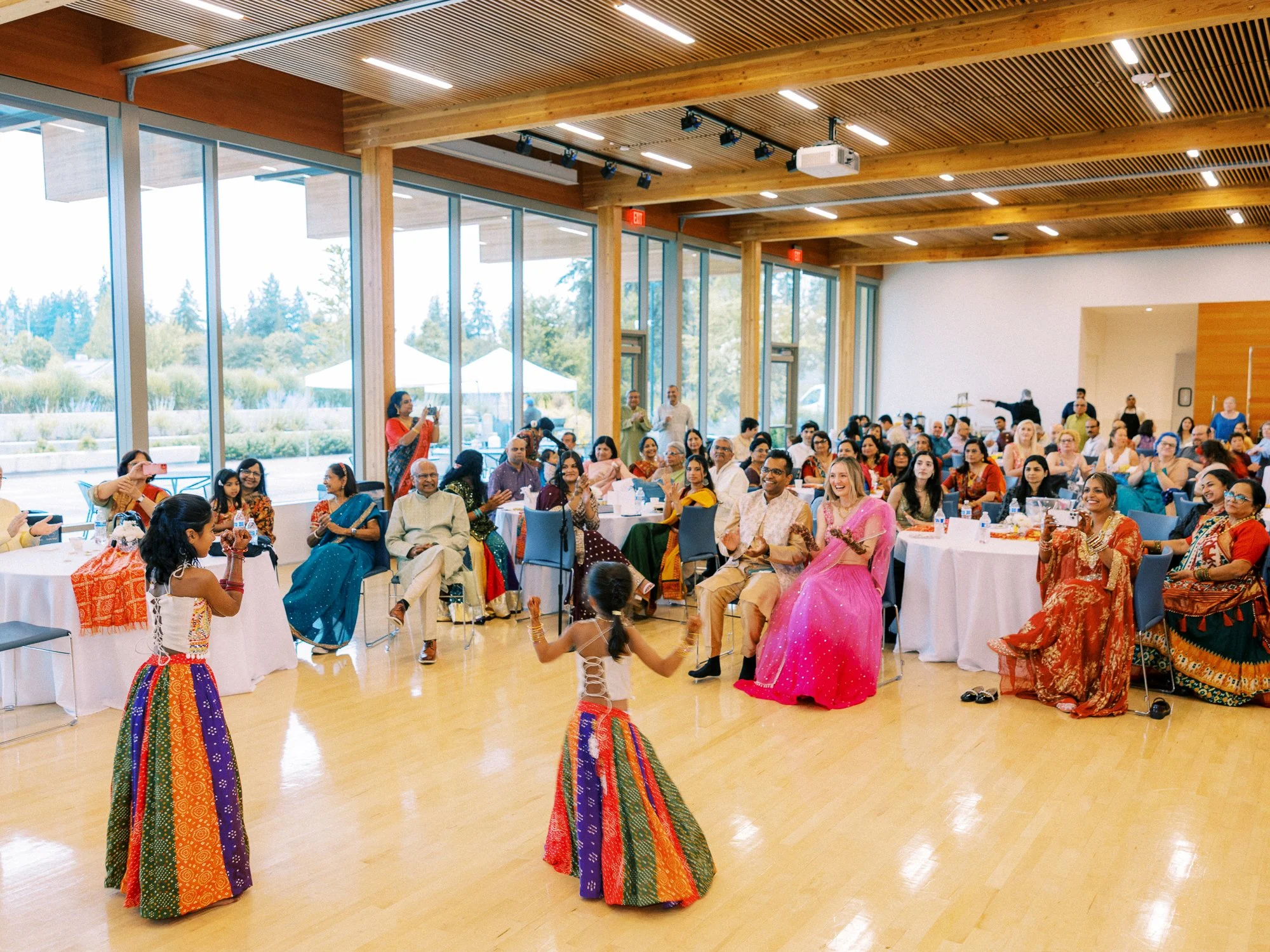 Two young girls perform a colorful dance as guests watch during the Mehndi celebration.