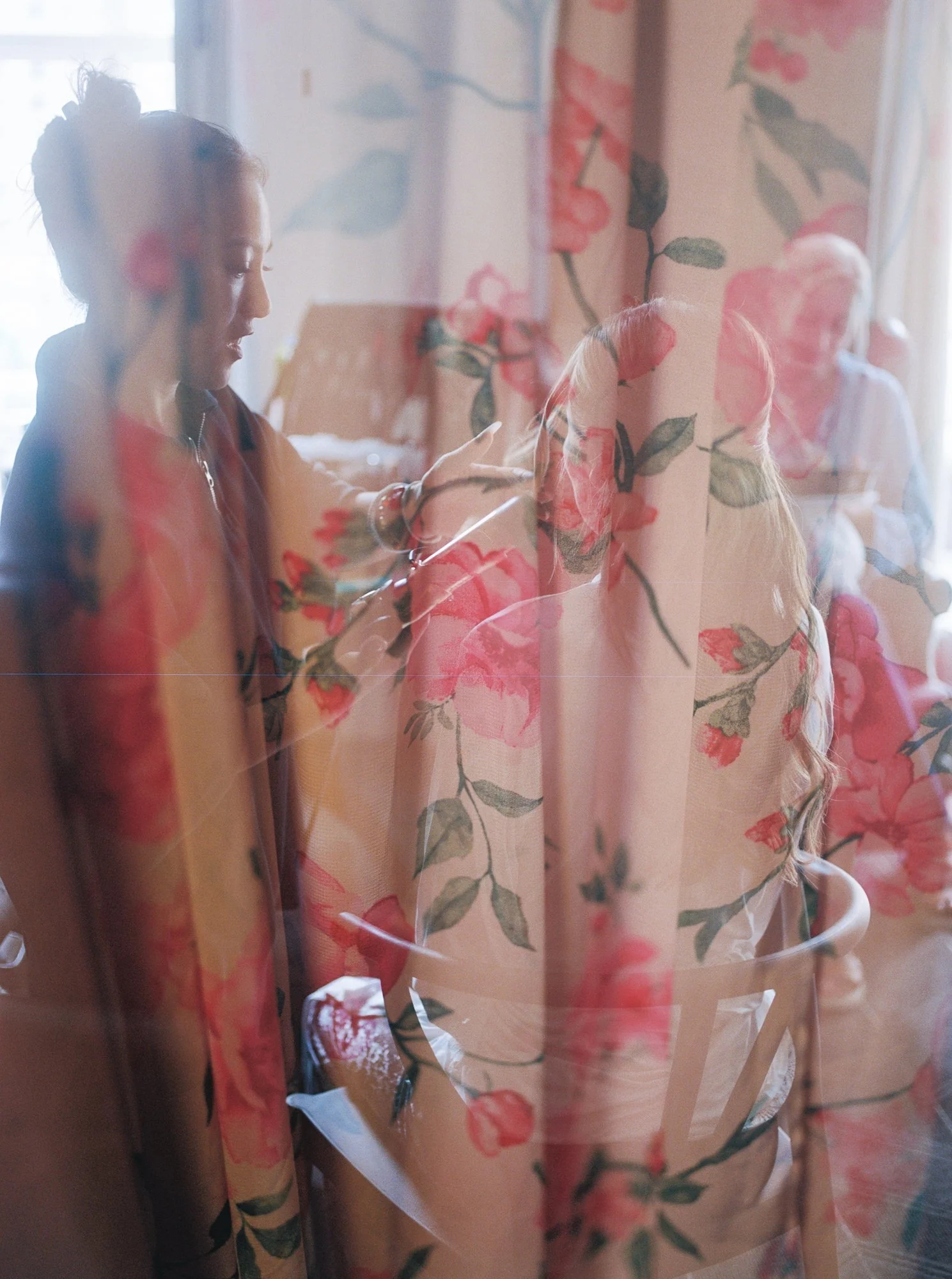 Getting-ready moment reflected through floral curtains inside a Sentinel Hotel room in Portland.