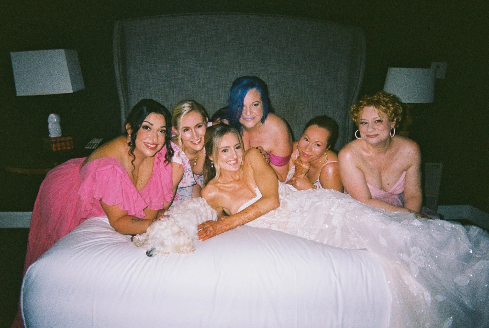 Alacia posing on the bed with friends in pink dresses and her small white dog at the Sentinel Hotel.