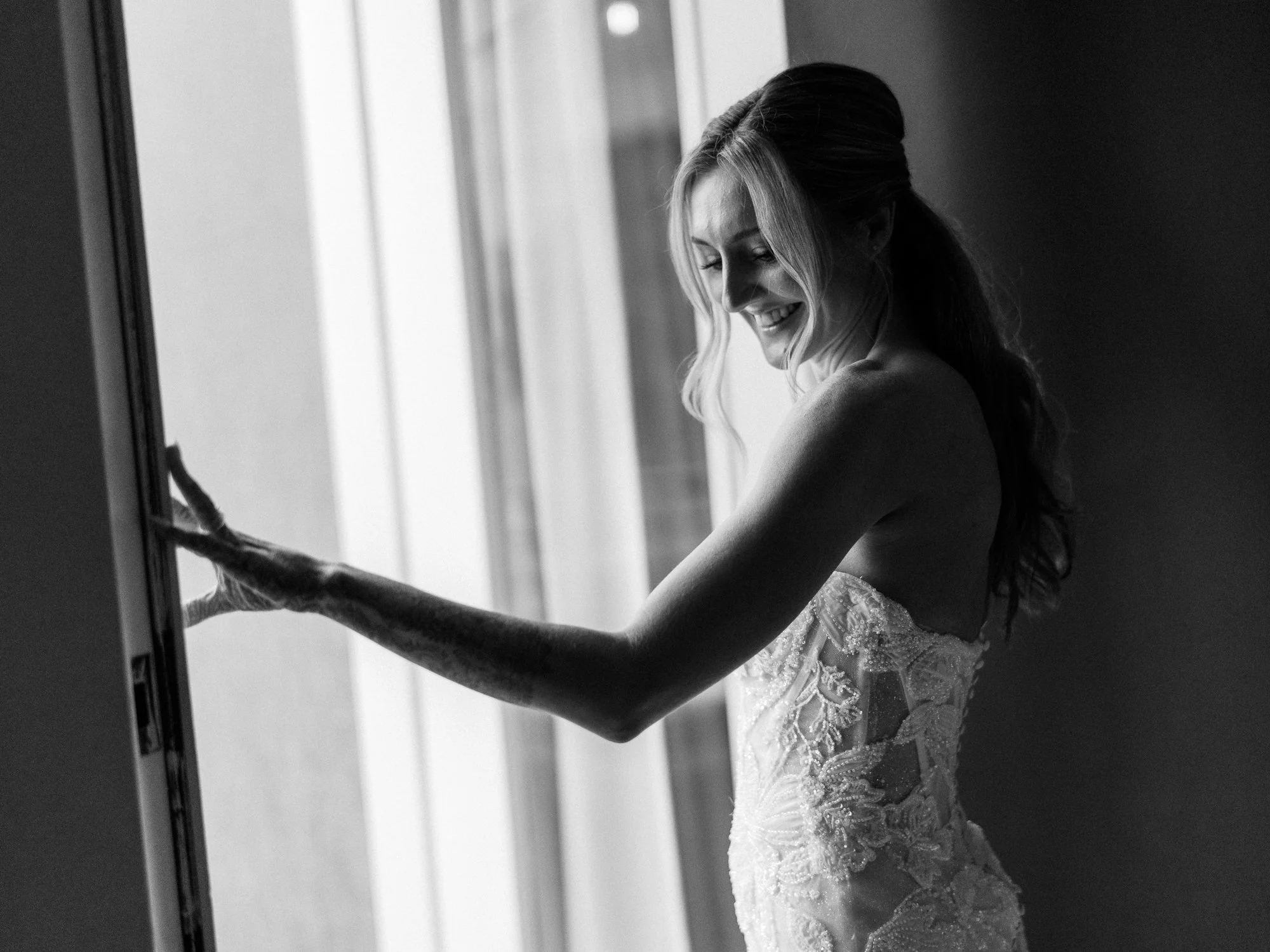 Black-and-white portrait of Alacia in her wedding dress beside a window at the Sentinel Hotel.