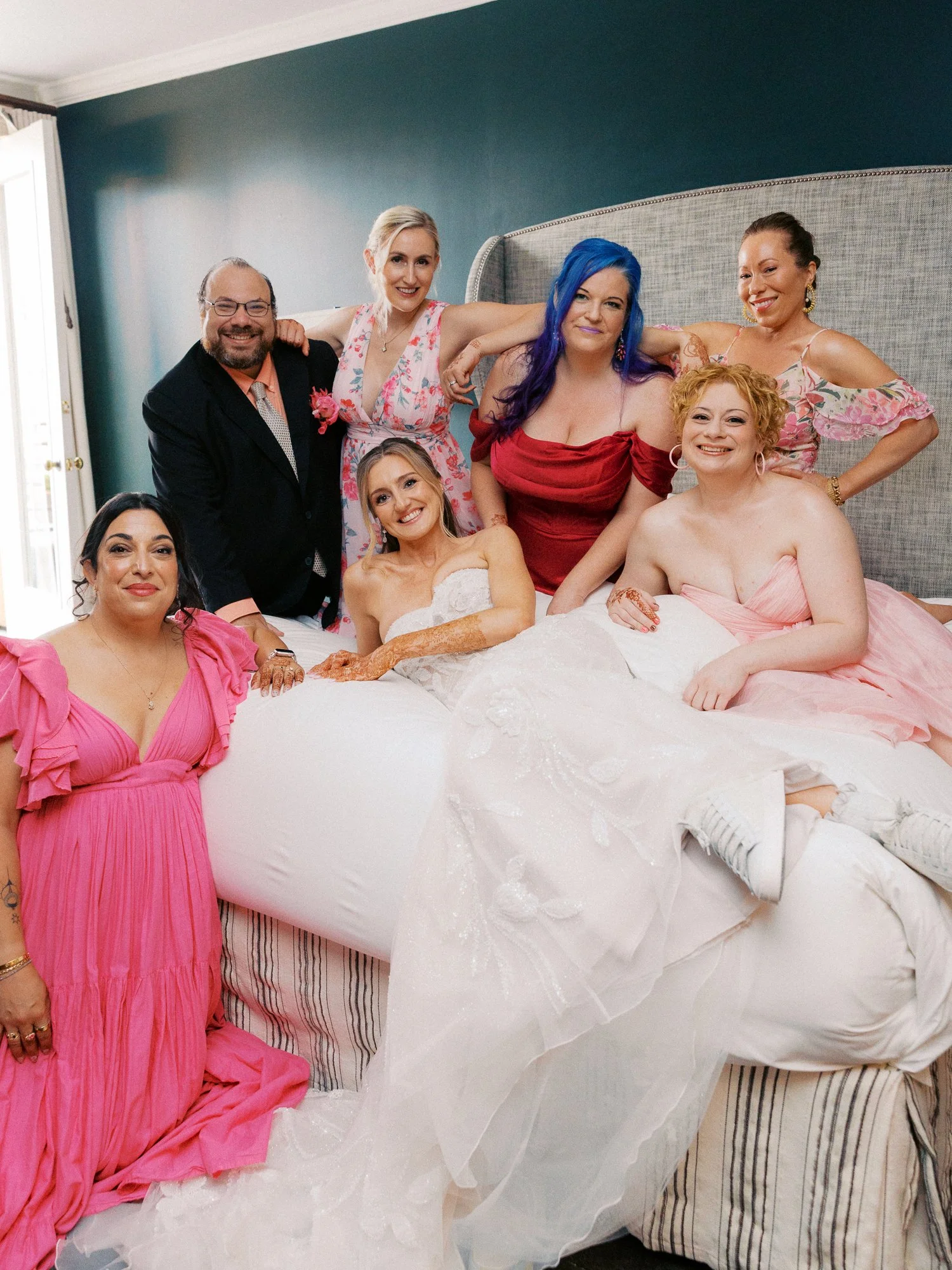 Alacia and friends posing together on the bed during wedding morning preparations at the Sentinel Hotel.