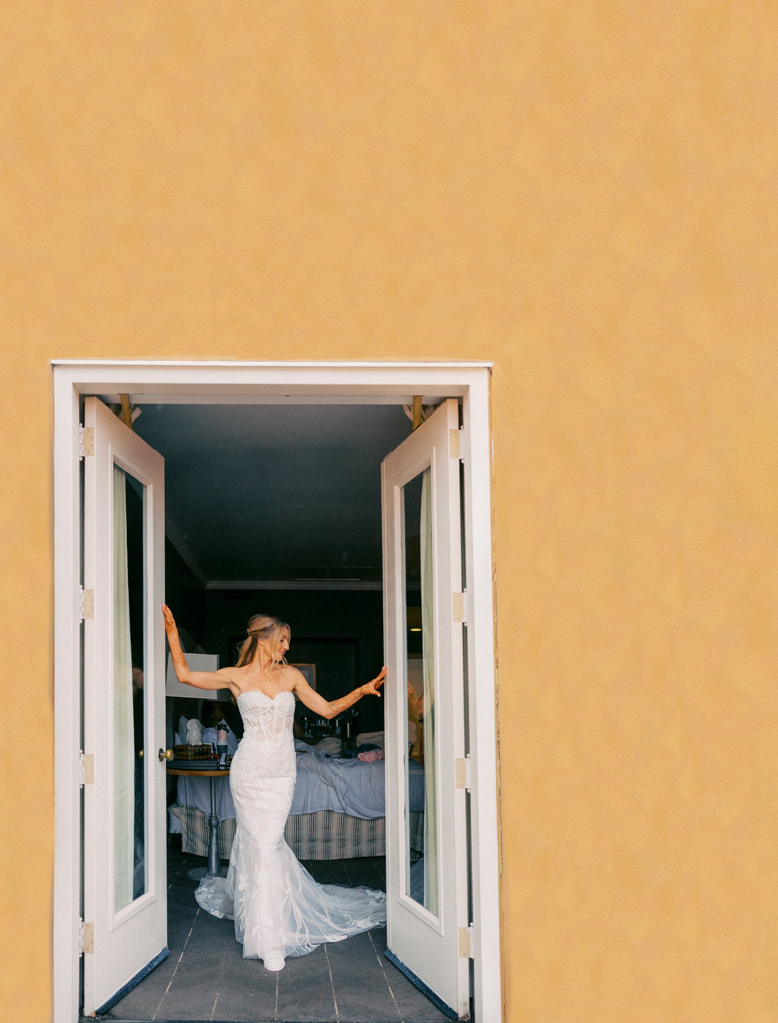 Alacia standing in her wedding dress between open balcony doors at the Sentinel Hotel in Portland.