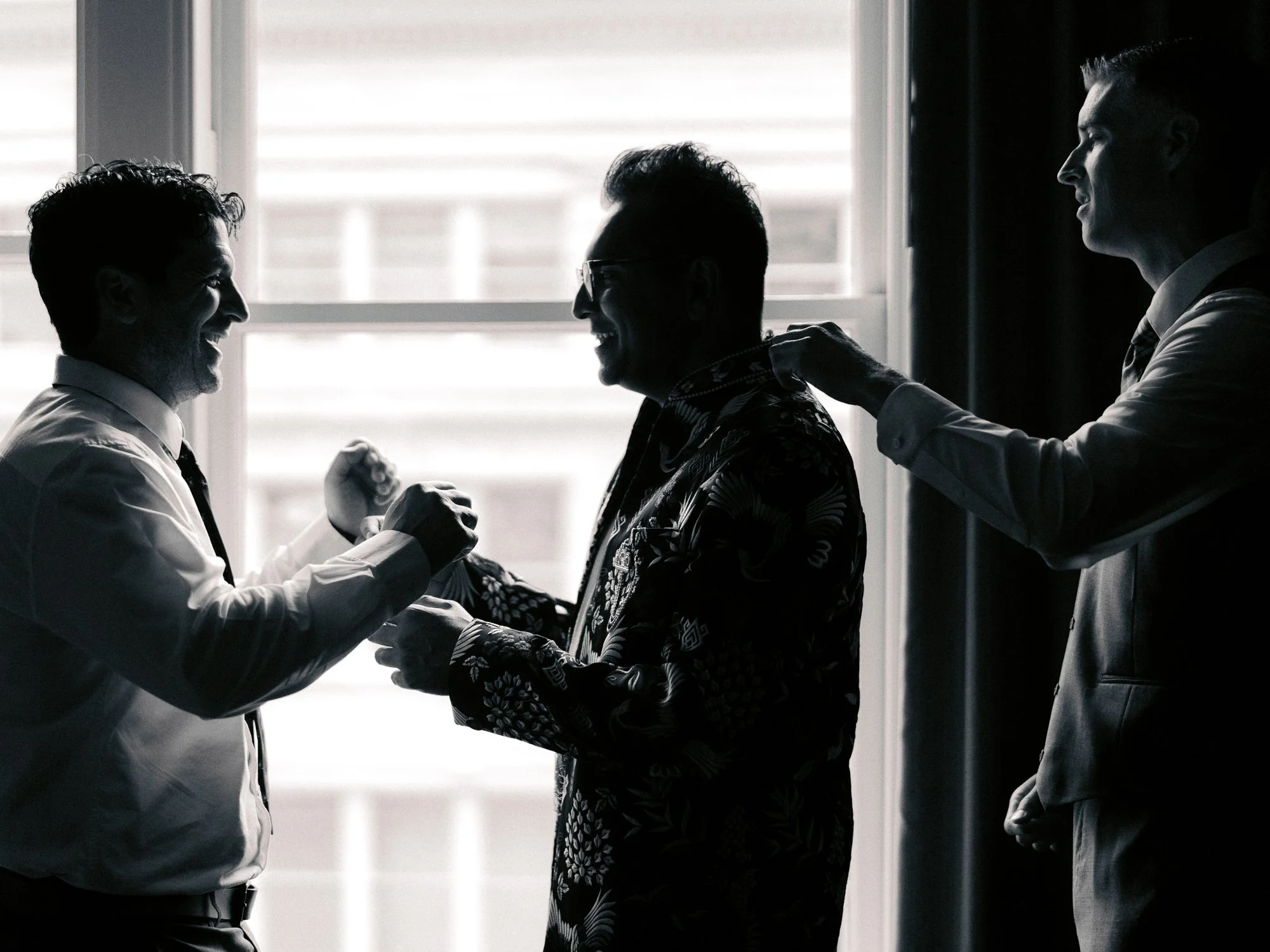 Groom and friends help with final wedding-day details beside a bright window at the Sentinel Hotel in Portland.