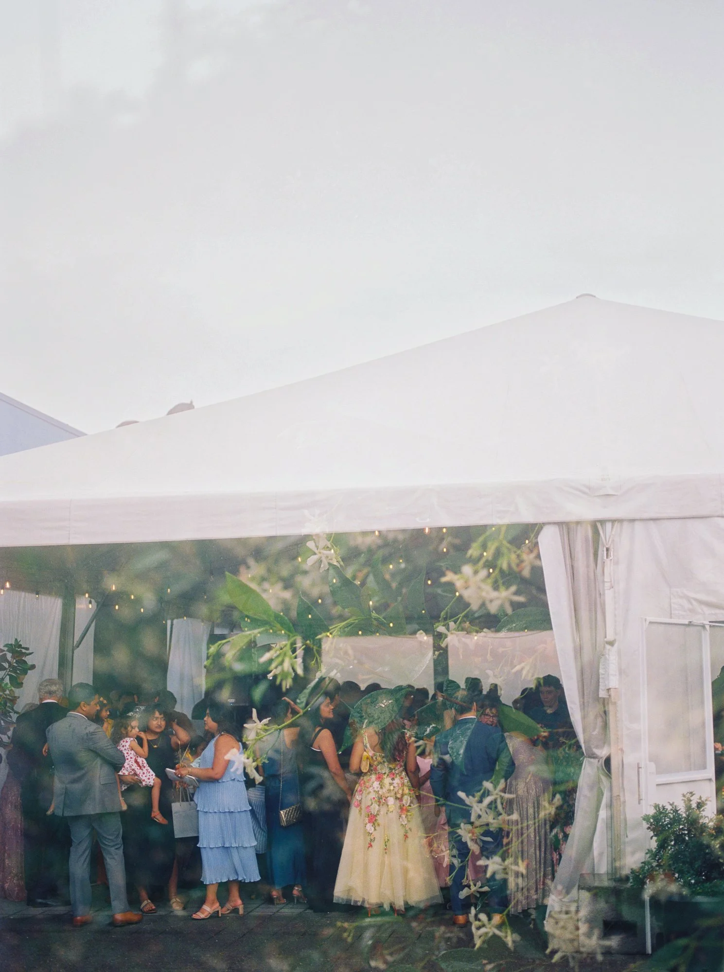 Guests gather beneath a white reception tent during a rainy wedding at Castaway Portland.