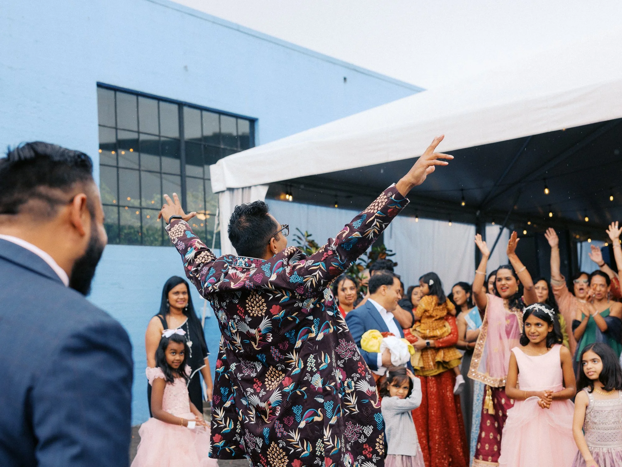 Groom dances with his arms raised as guests gather around him outside Castaway Portland.