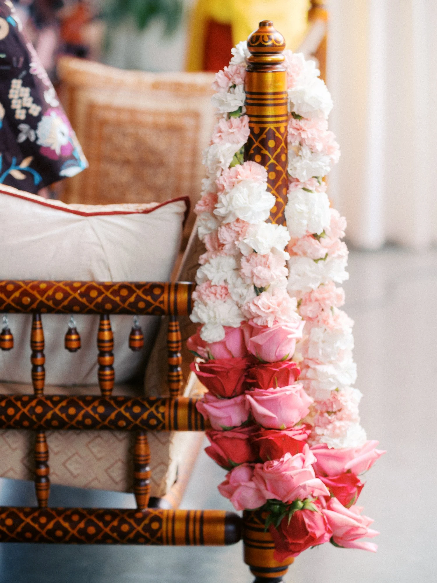 Pink and white floral garland drapes over a carved wooden ceremony chair.
