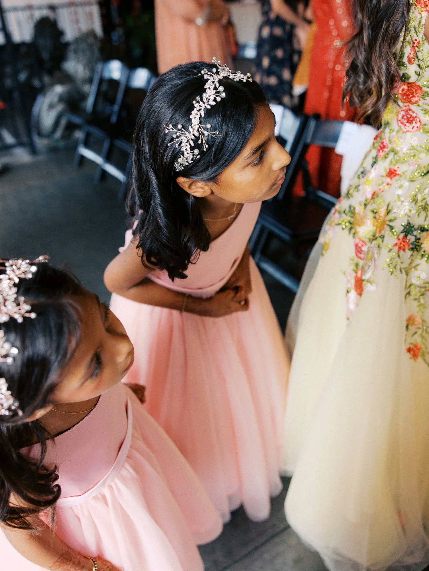 Two flower girls in pink dresses look toward a guest during the ceremony.