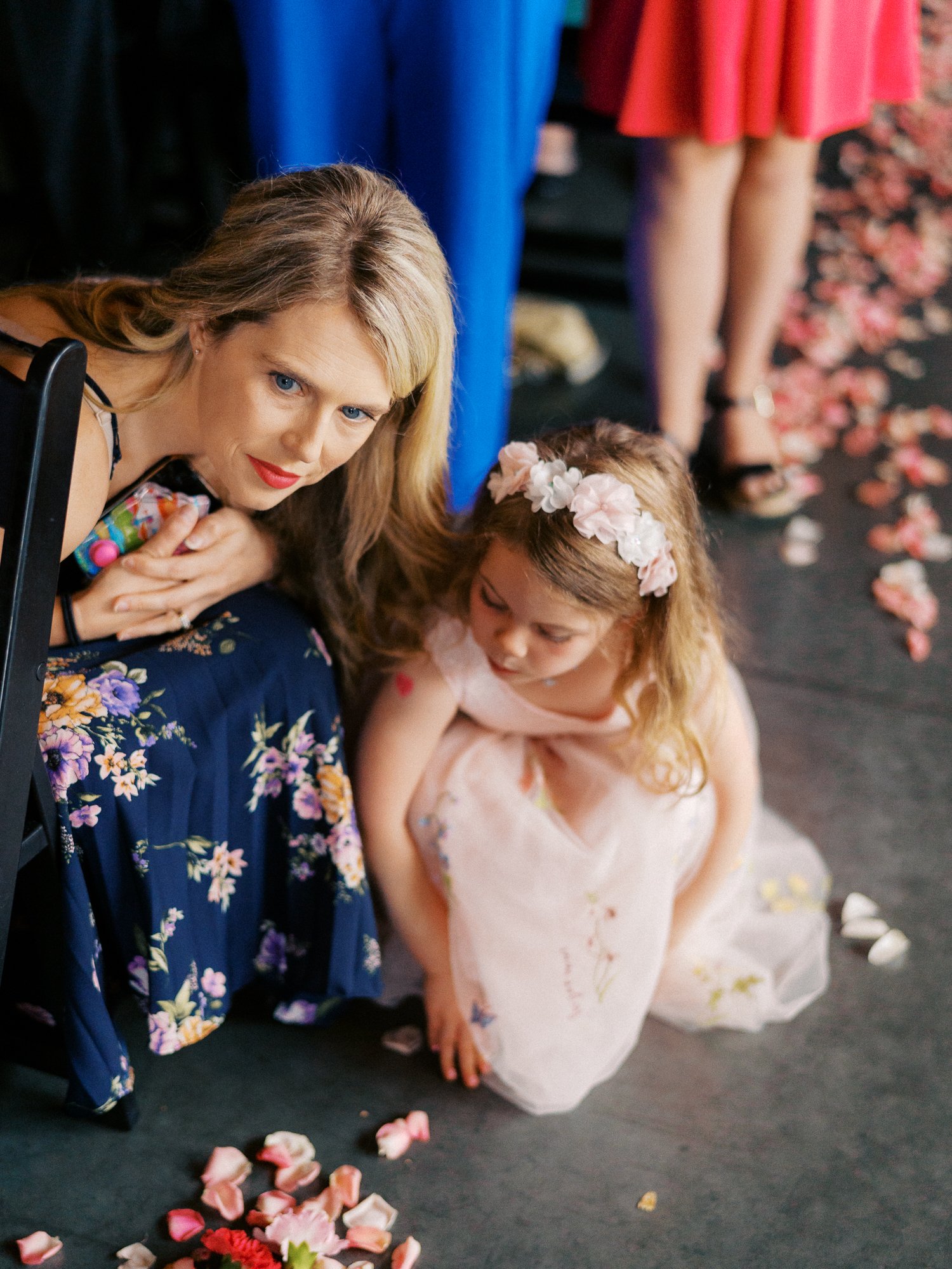 Woman and young girl sit beside scattered flower petals during the ceremony.