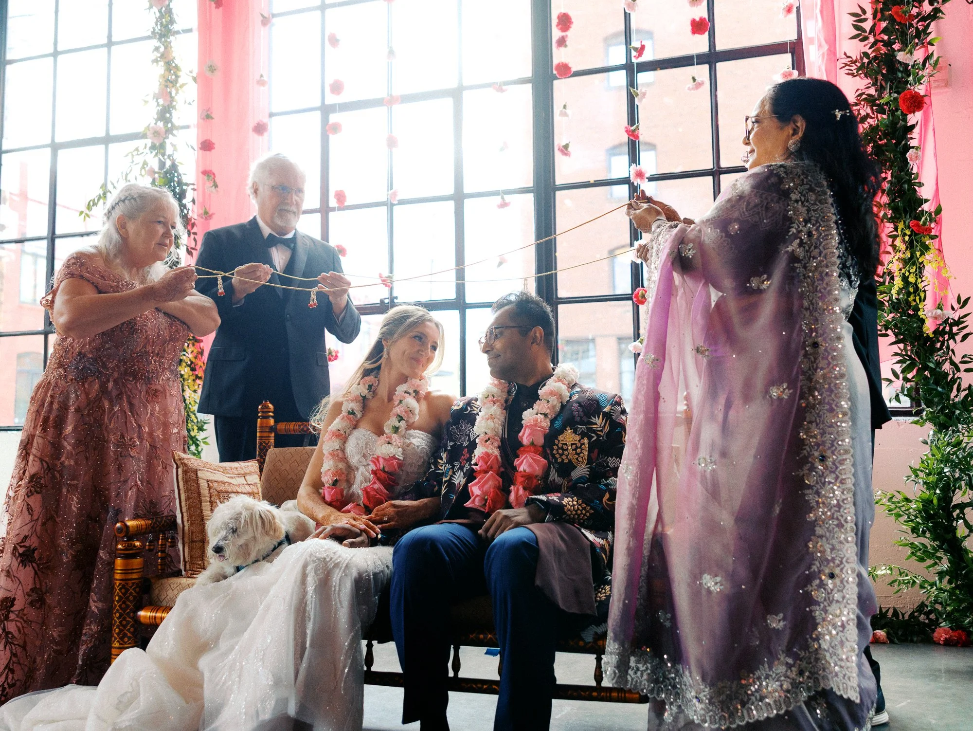 Family members hold ceremonial cords above the seated bride and groom.