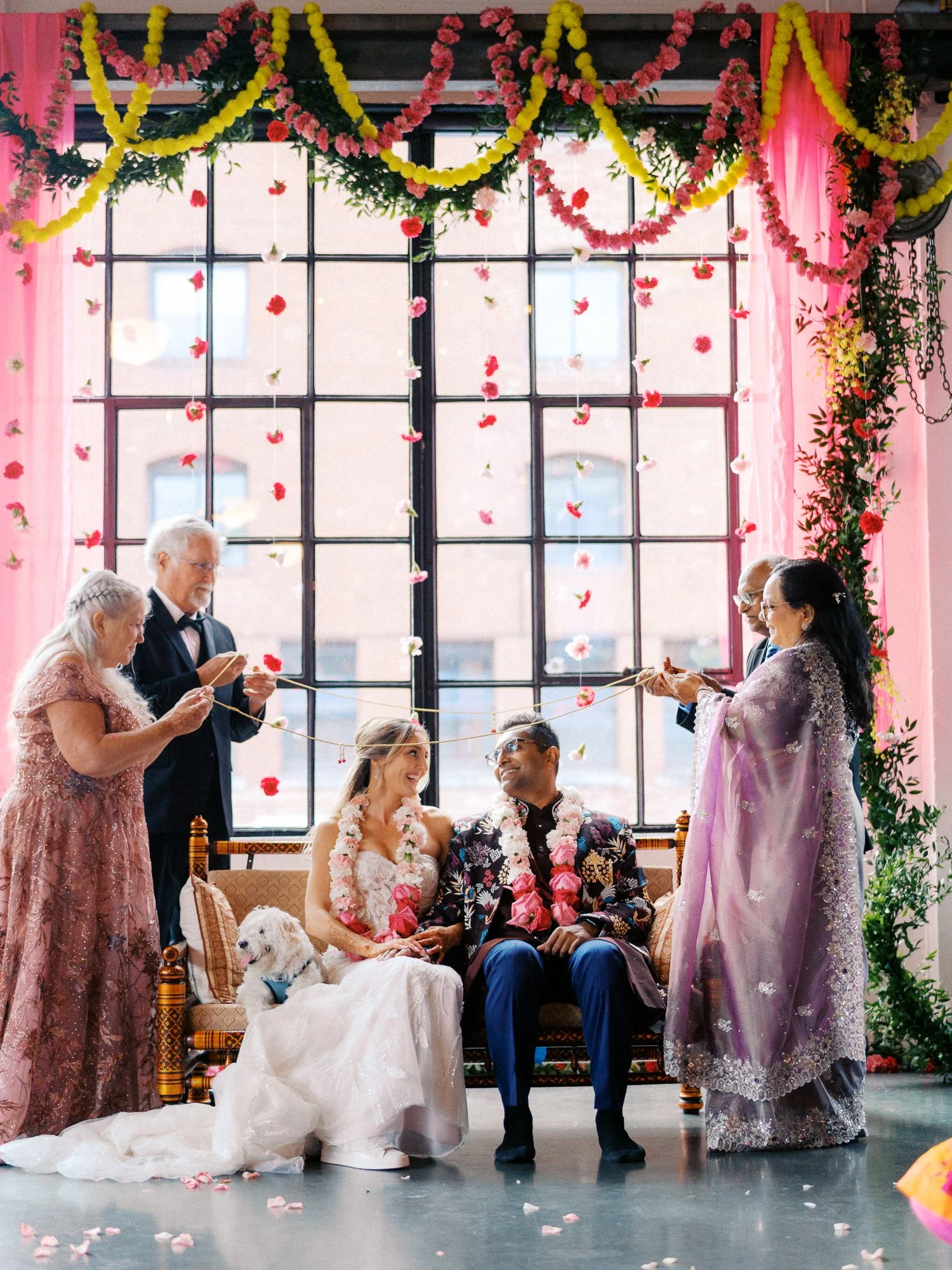 Family members hold ceremonial cords above the seated bride and groom.