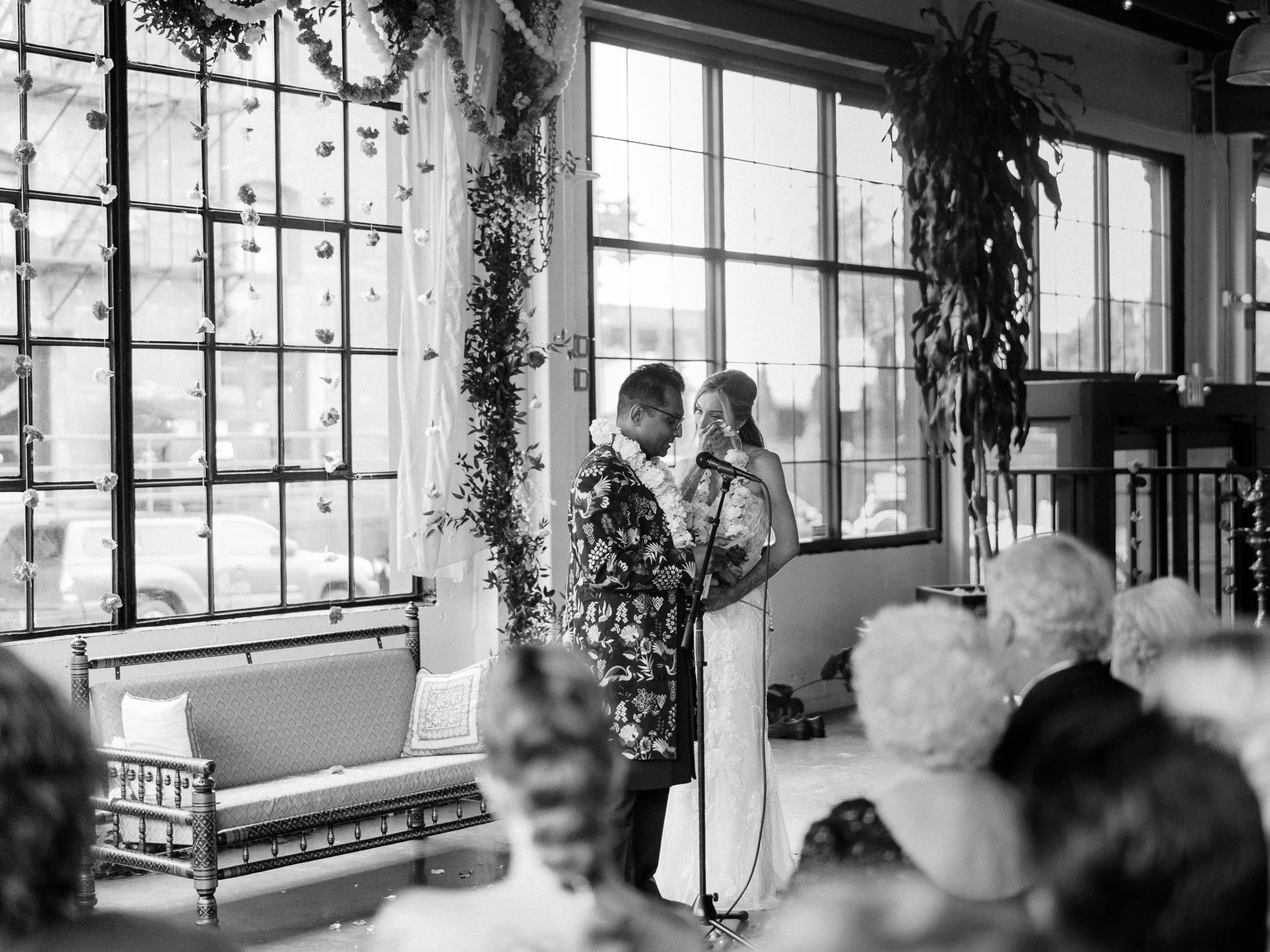Black-and-white photo of the couple standing at the microphone during their wedding ceremony.