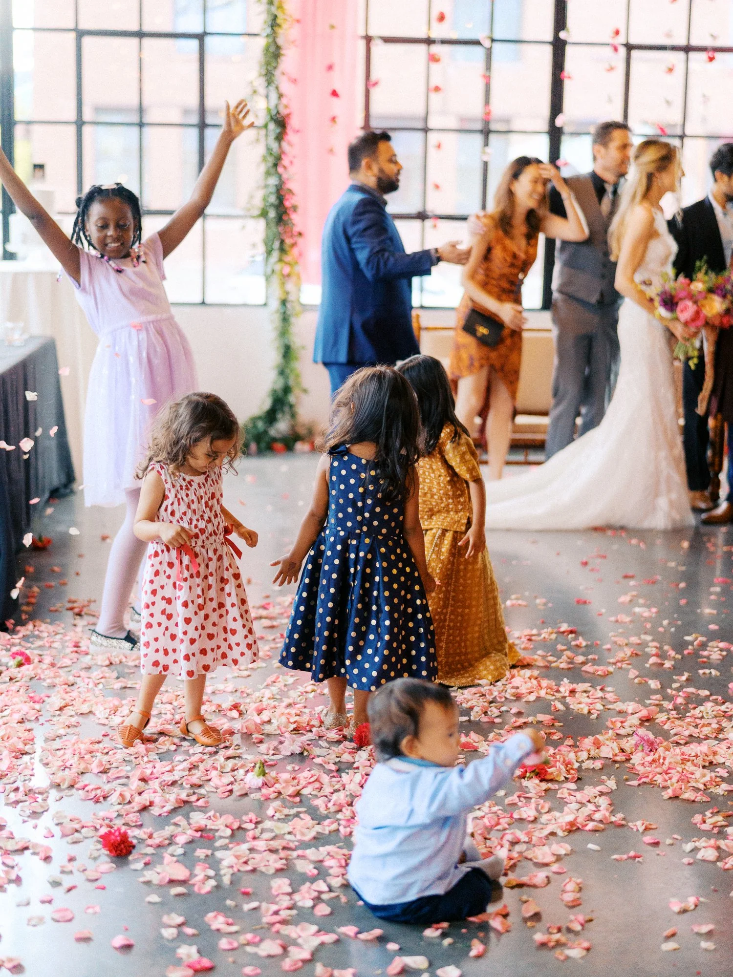 Children toss and gather flower petals while guests mingle in the background.