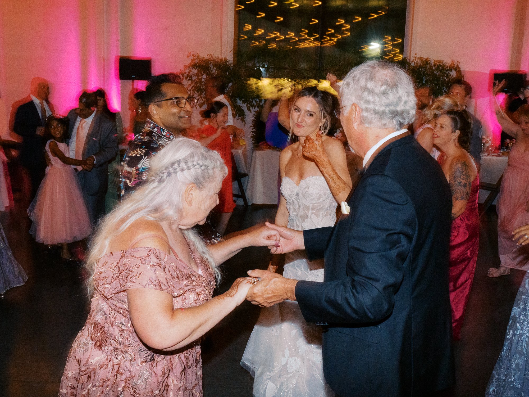 Bride dances with family members while the groom and other guests gather nearby.