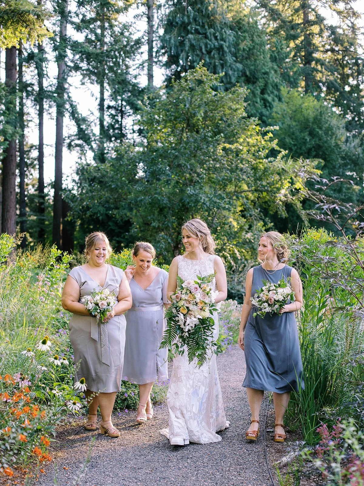 Bride and bridesmaids walk down a garden path.