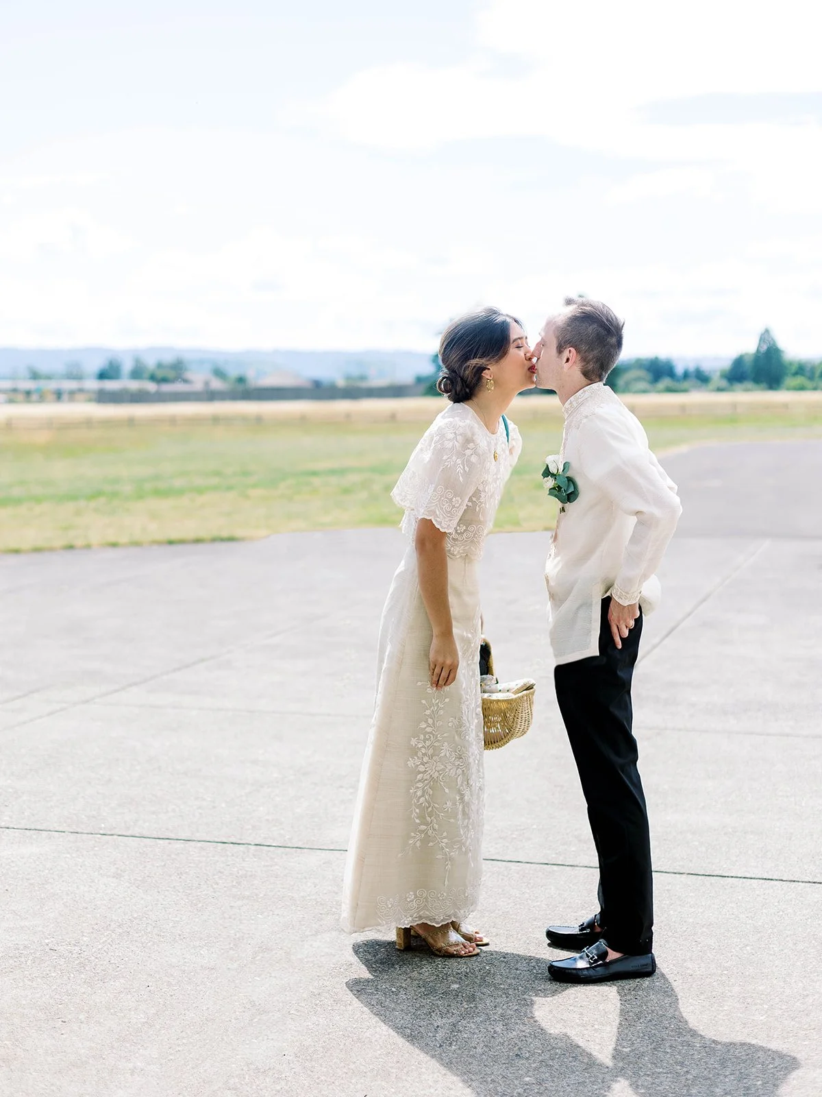 Bride and groom sharing a kiss on the Pearson Airfield tarmac, both in Filipino traditional wedding attire
