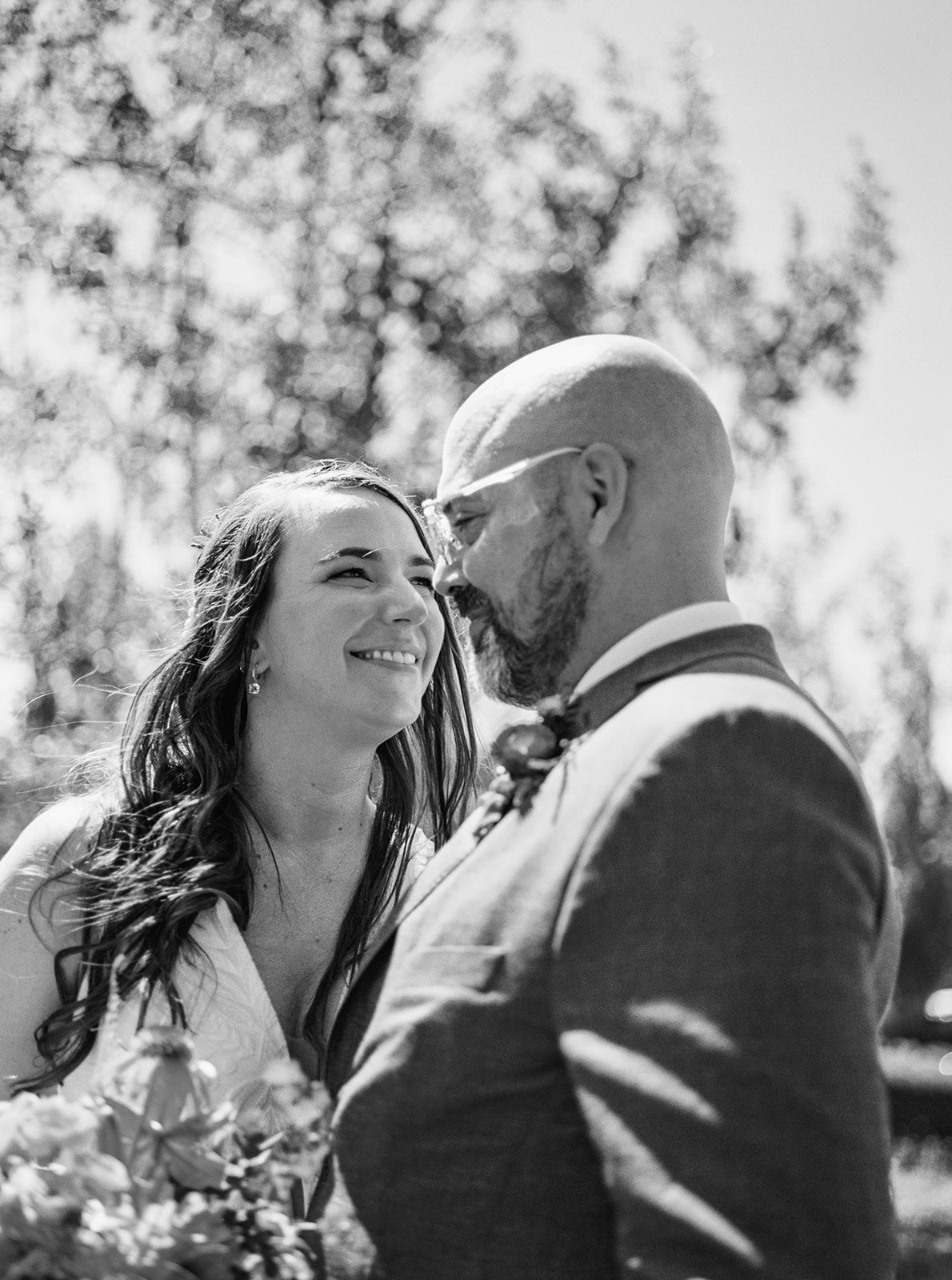 Black and white close-up of bride and groom smiling face to face outdoors