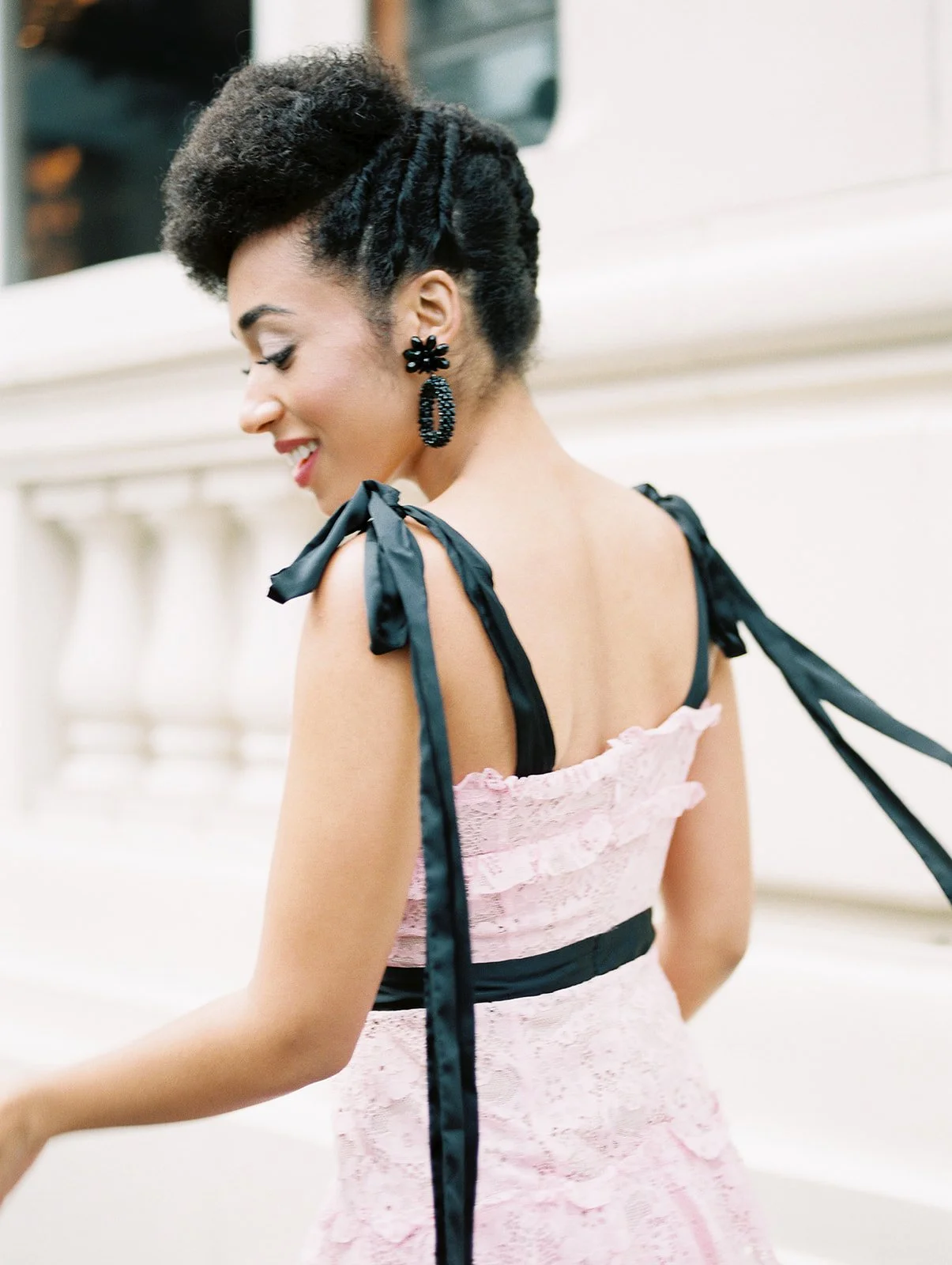 Close-up of woman in pink dress with black ribbon straps walking along Portland street