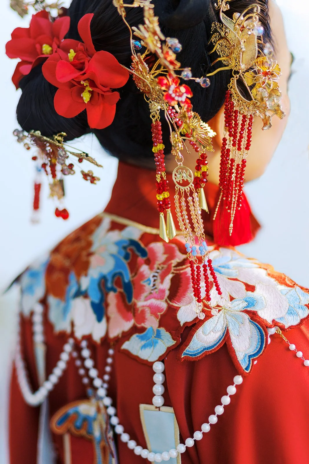 Detailed view of ornate gold and red hair ornaments cascading from a styled bridal updo
