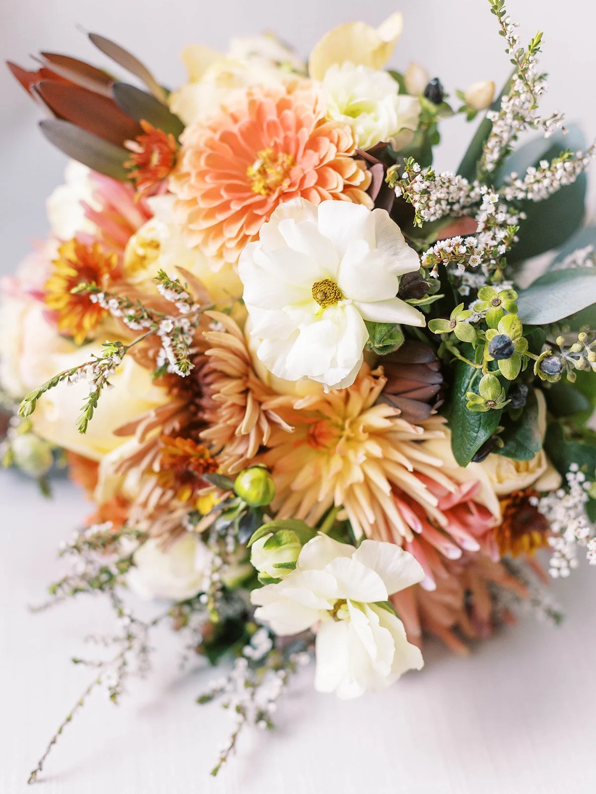 Garden-style wedding bouquet with peach, ivory, and greenery florals arranged on a light surface at Oregon Gardens.