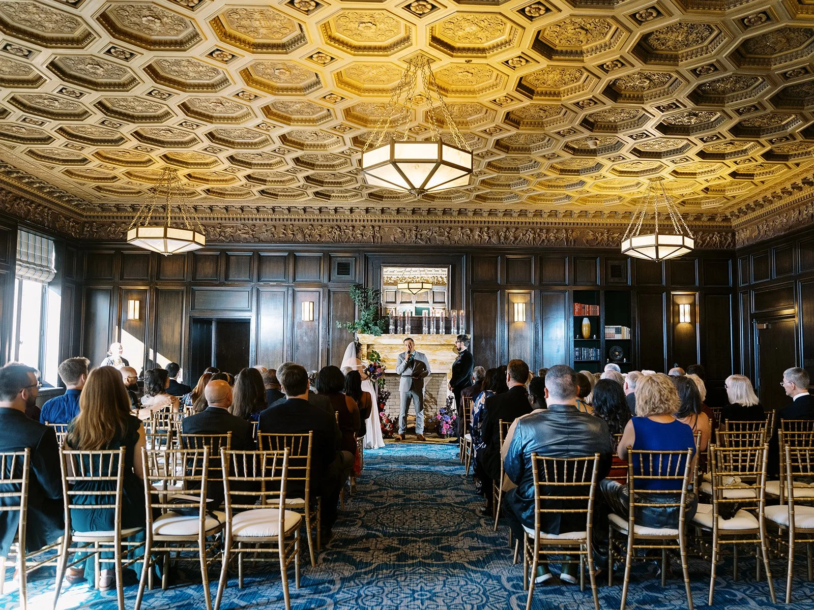 Wedding ceremony in wood-paneled ballroom with ornate gold coffered ceiling at the Sentinel Hotel in Portland.