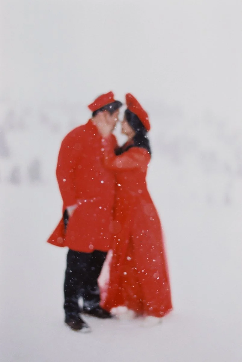 Soft-focus silhouette of couple in Vietnamese áo dài embracing during snowfall at Mount Hood.