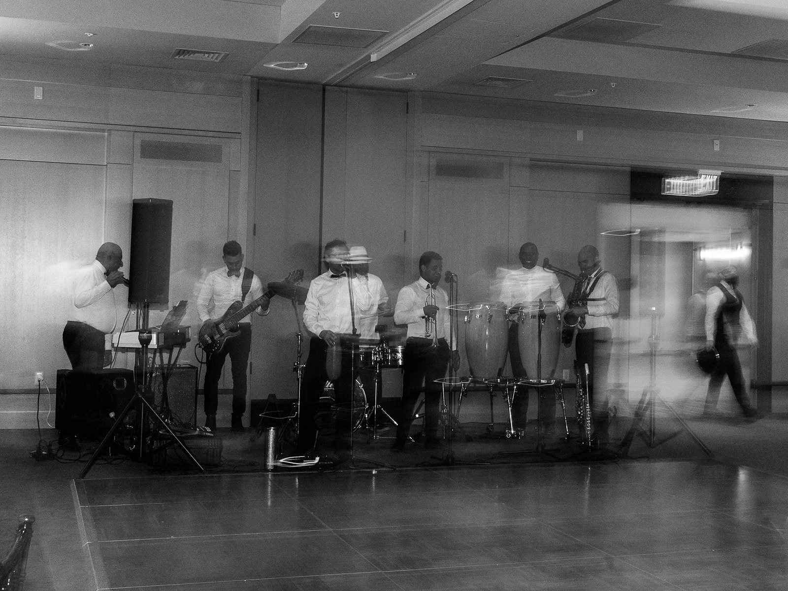 Black and white long-exposure photo of the live band performing, with motion blur conveying the energy of the music