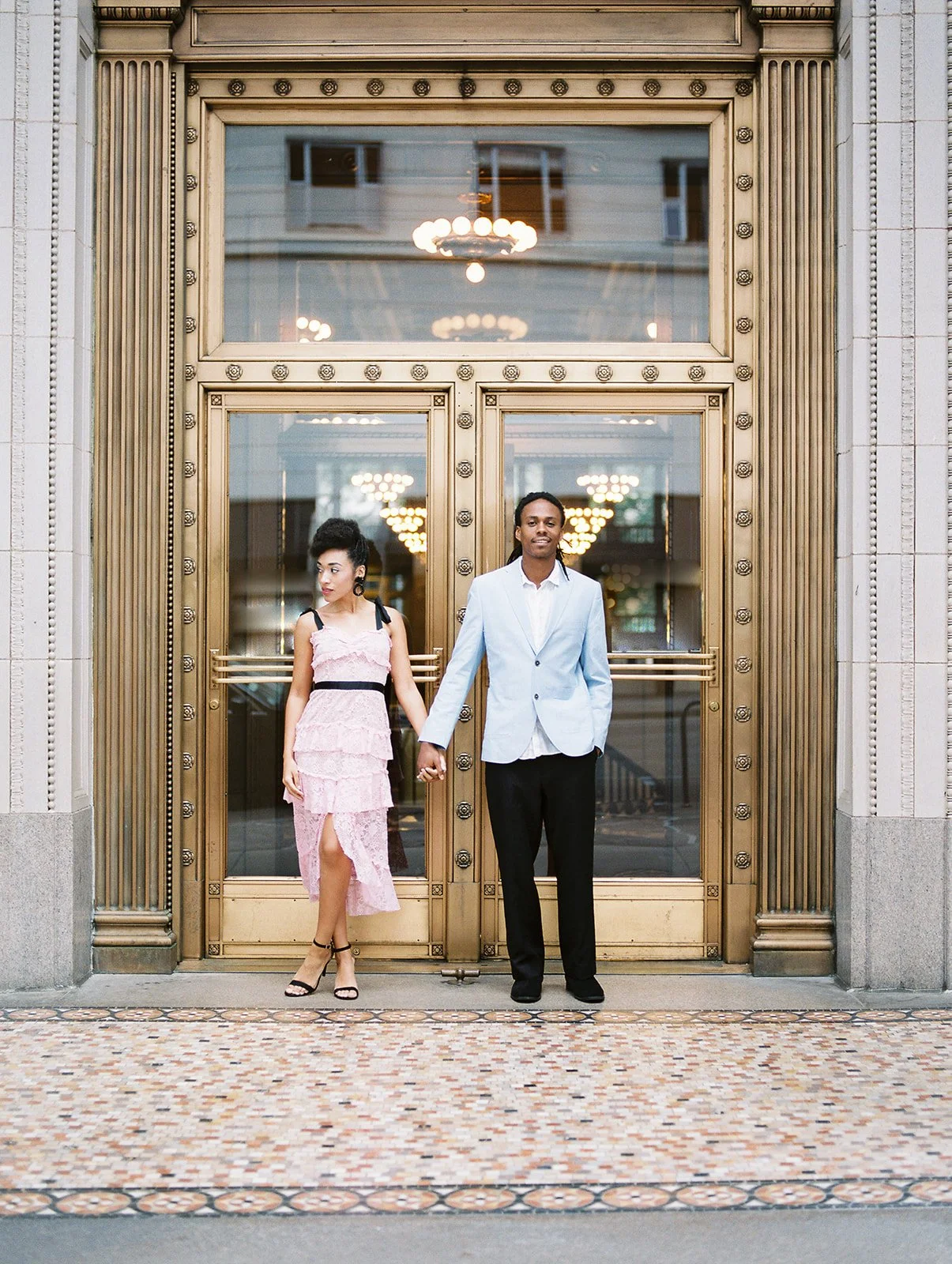 Couple standing in front of ornate hotel entrance in downtown Portland, dressed in formal attire