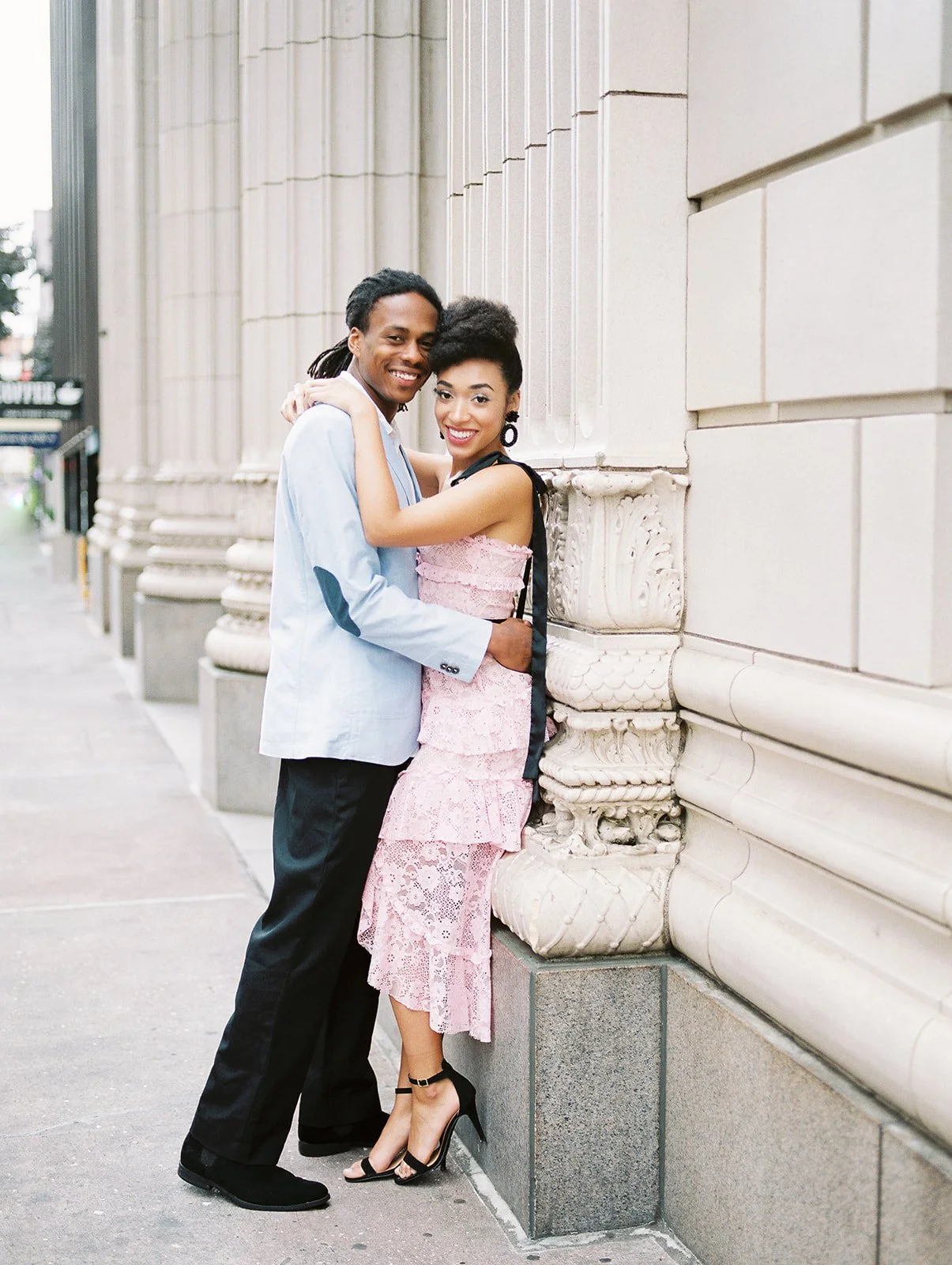 Couple holding hands outside historic Portland building with gold doors and tiled entryway