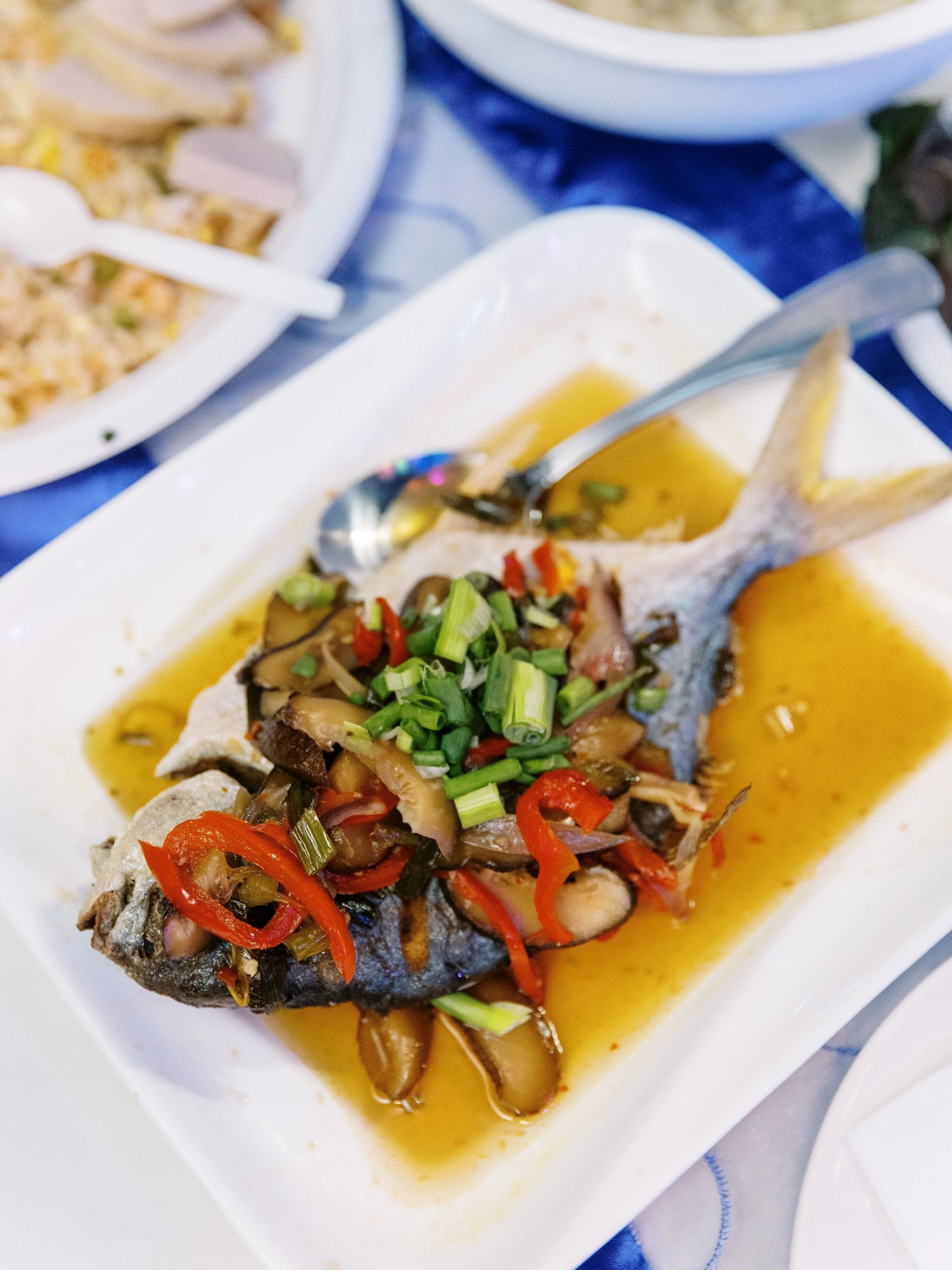 Whole cooked fish topped with mushrooms, peppers and green onions served at a wedding meal.