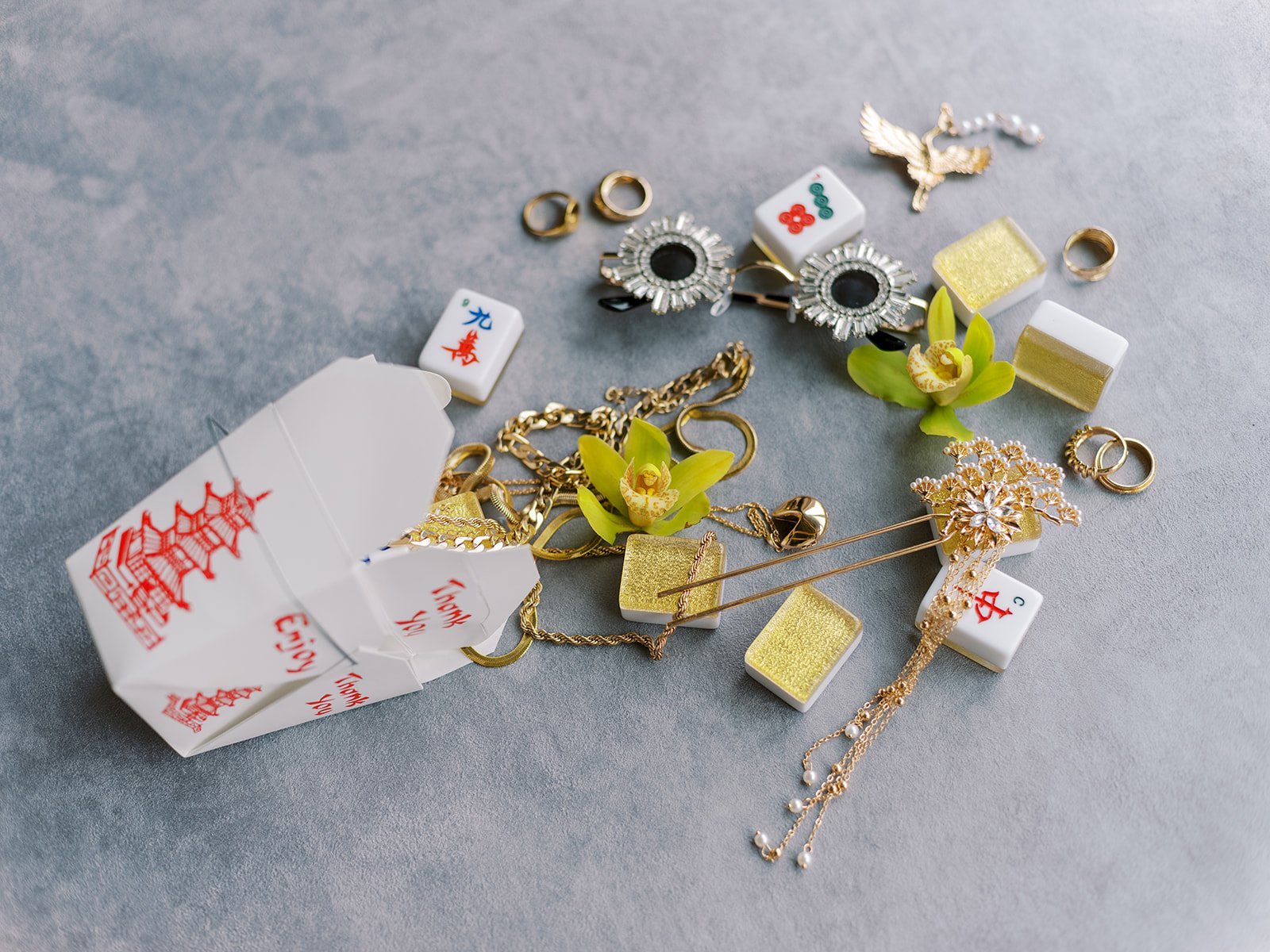 Flat lay of mahjong tiles, gold jewelry, orchids, and accessories styled together for a couture bachelorette party at Lan Su Chinese Garden in Portland.