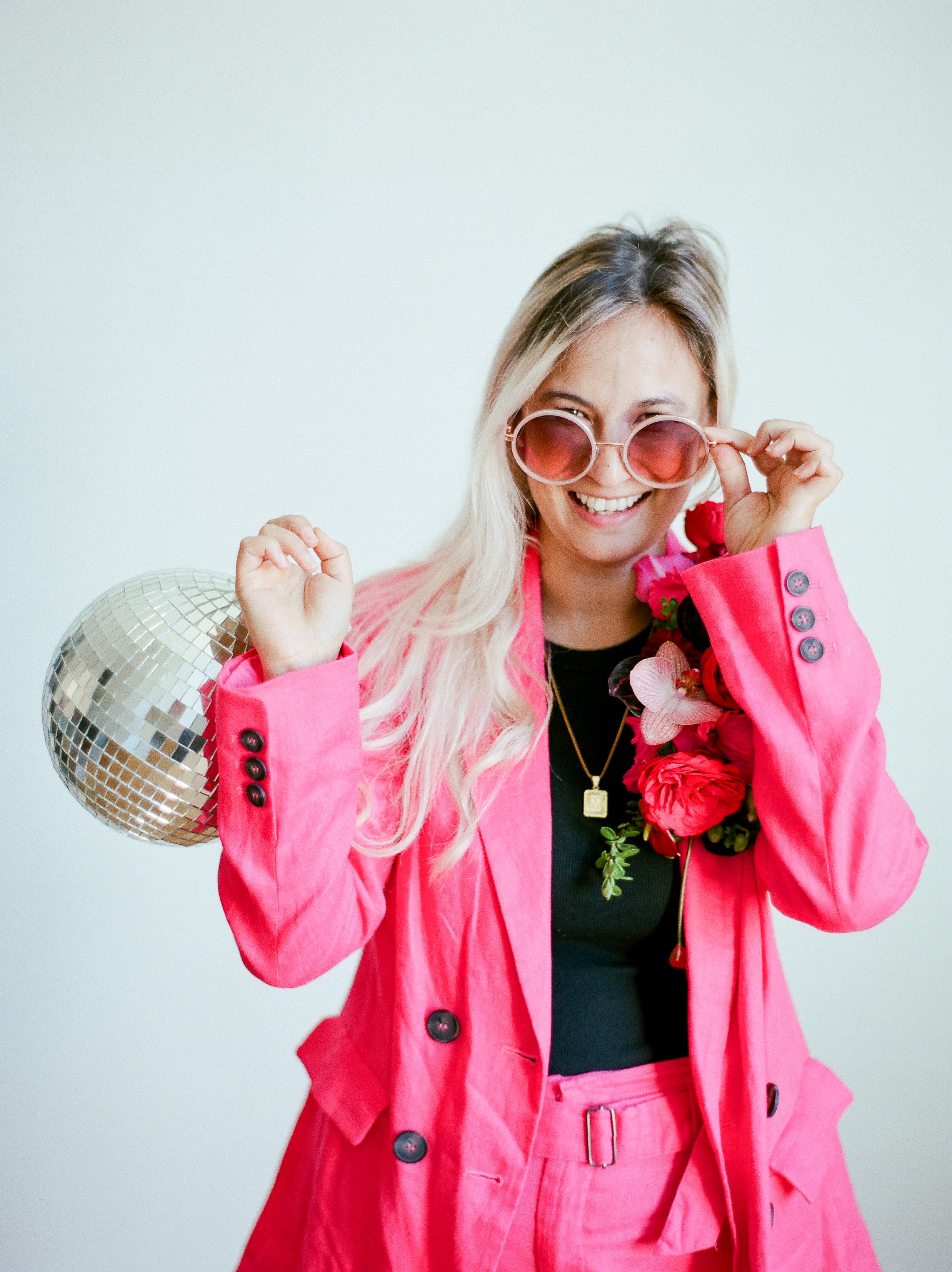 Portland wedding photographer Mylyn Wood in a bright pink suit with a disco ball and floral details.