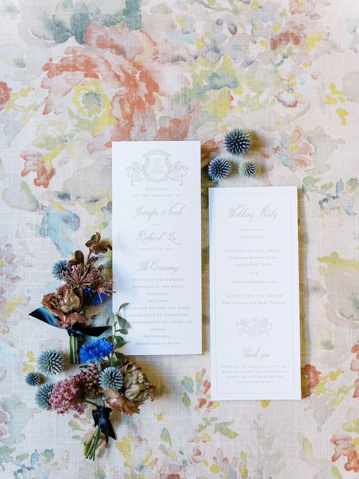 Wedding ceremony programs and floral boutonniere arranged on a colorful patterned fabric background.
