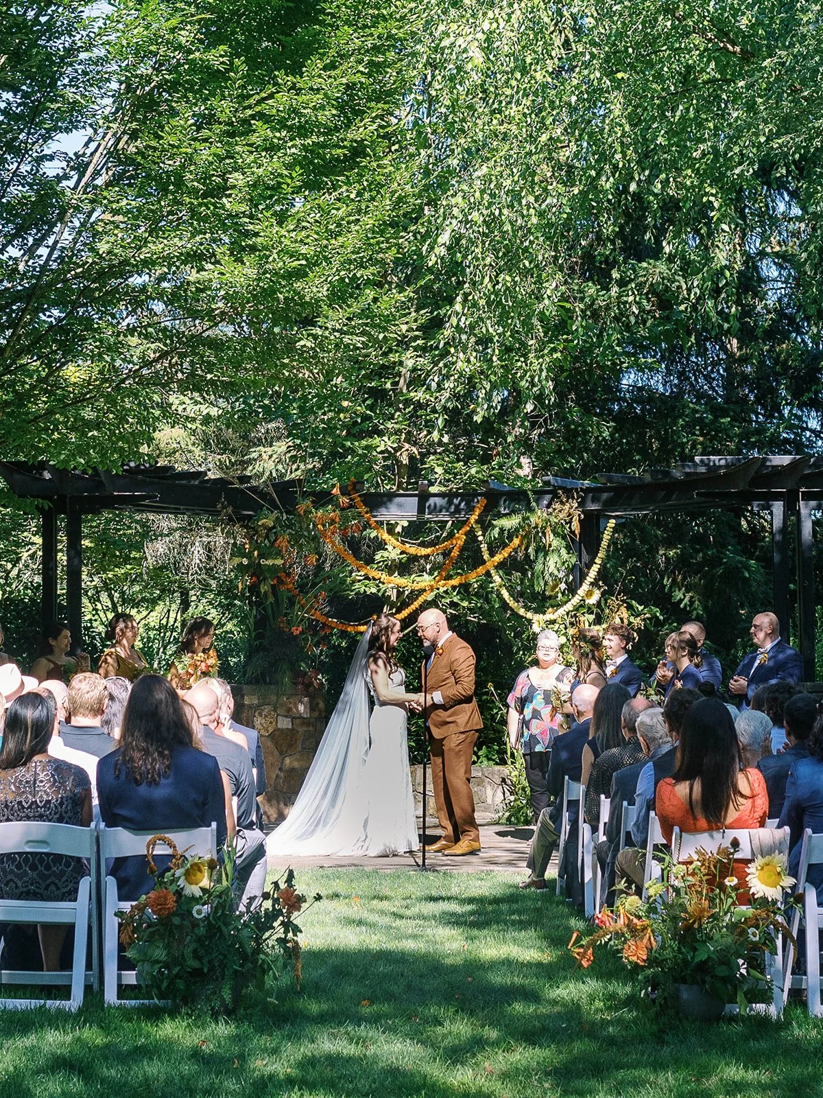 Newlyweds walk down the aisle after ceremony, bride holding bouquet and groom raising his hand in celebration.
