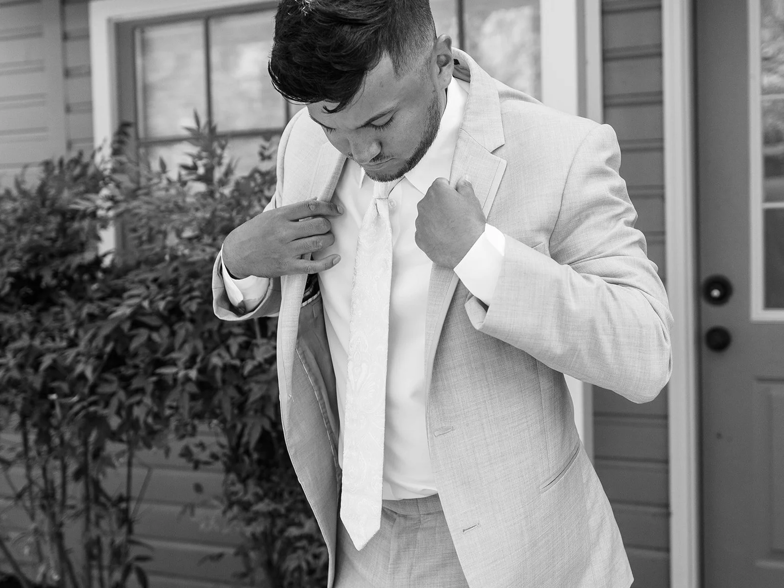 Groom adjusting light gray suit jacket before ceremony outside Abernathy Center.