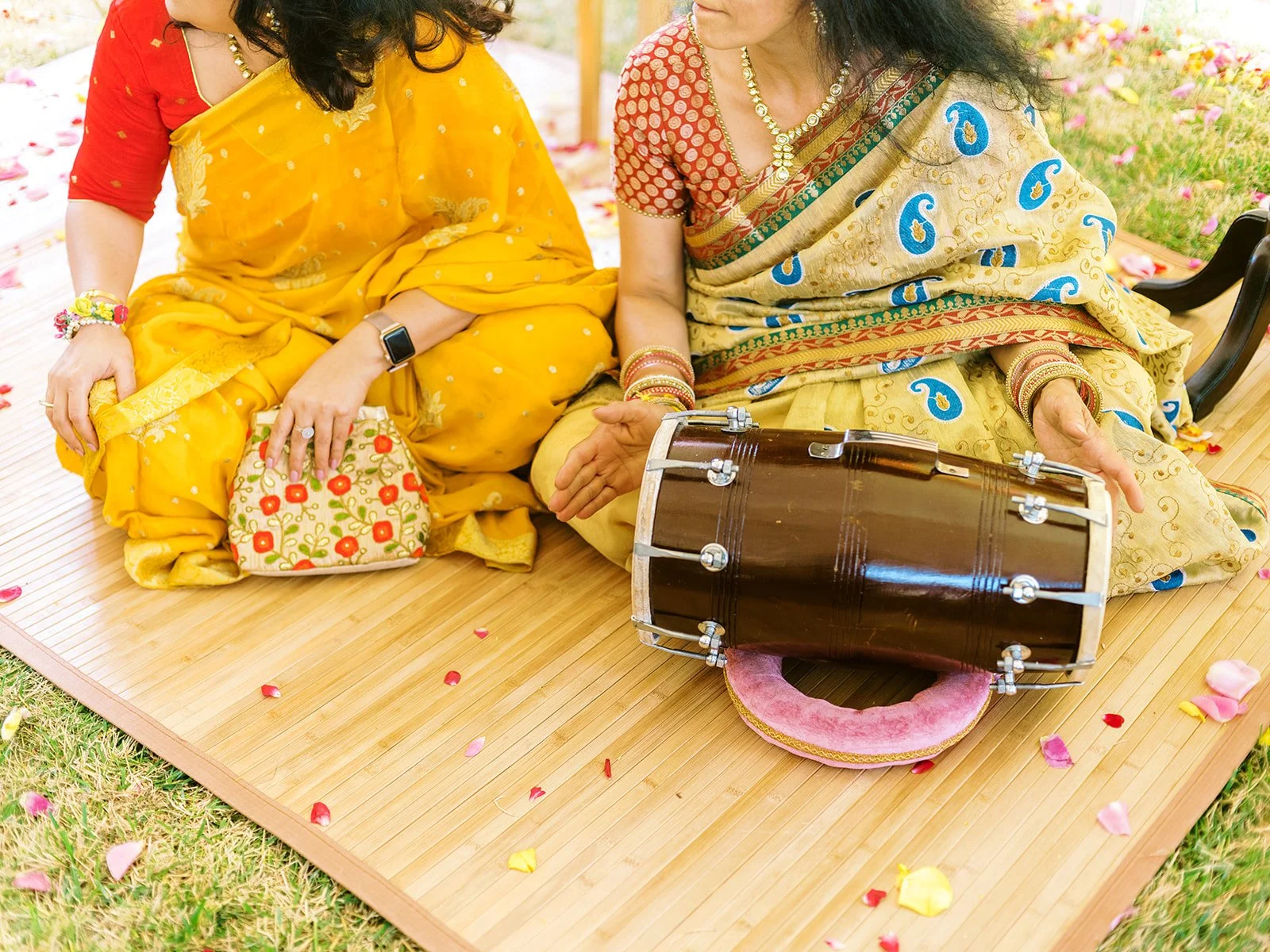 women dressed in saari's on a bamboo mat with a dholak drum