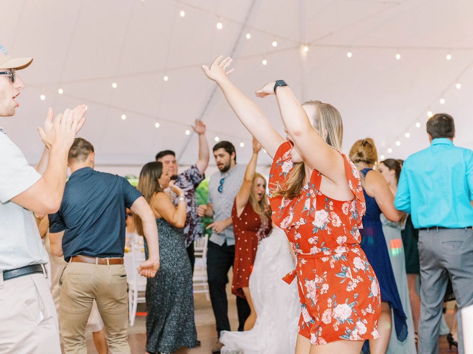 Wedding guests dance under a reception tent.