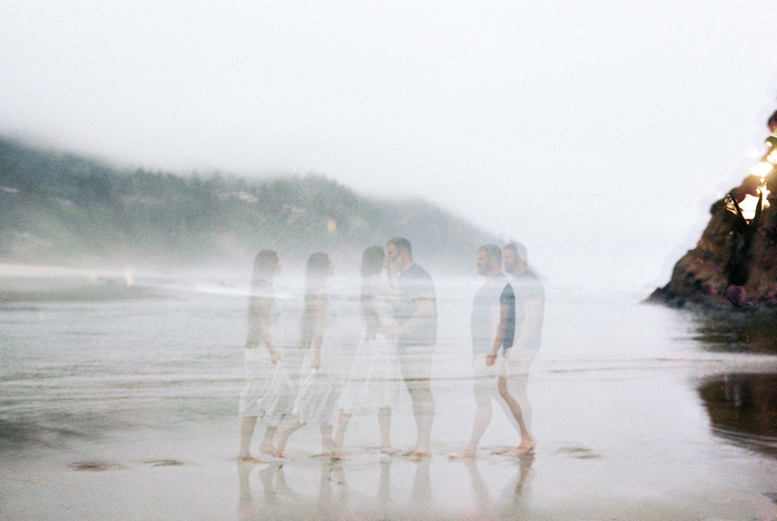 Creative multi-exposure of couple walking together along foggy shoreline with reflections in wet sand.