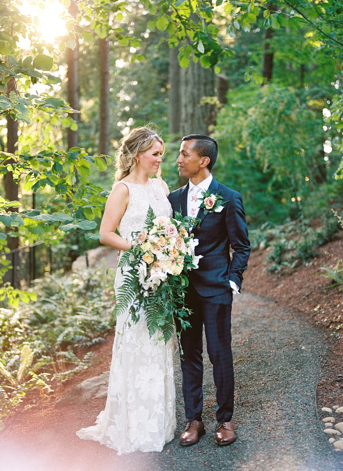 Bride and groom stand together on a wooded path at Leach Botanical Garden in Portland.