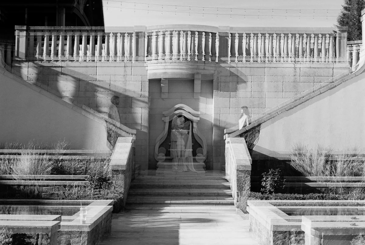 Artistic black-and-white double exposure portrait of couple layered with architectural courtyard details.