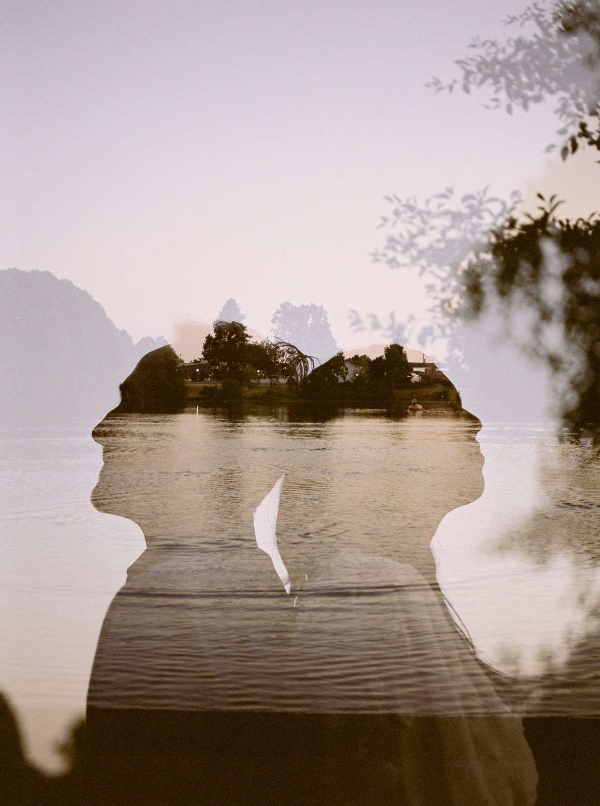 Double exposure silhouette of couple by water with sunset tones, creative engagement portrait