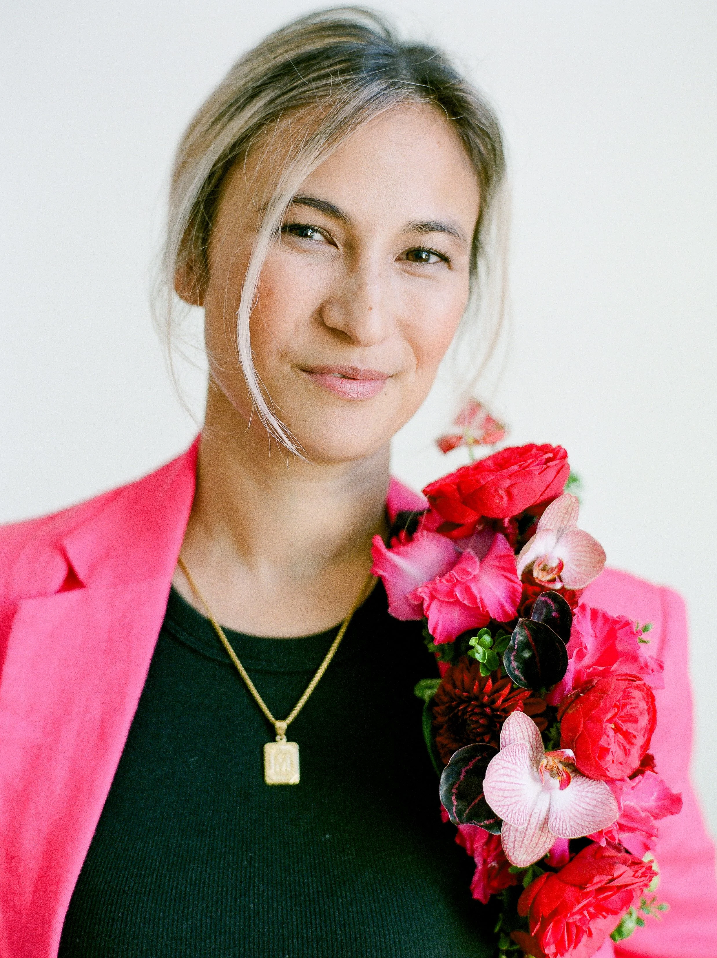 Portland wedding photographer Mylyn Wood in a pink blazer holding a colorful bouquet of flowers.