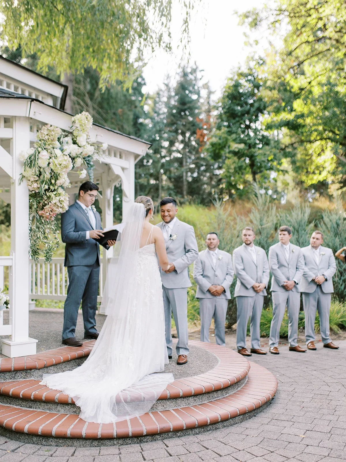 Bride and groom exchanging vows beneath floral gazebo at Abernathy Center Abigail’s Garden.