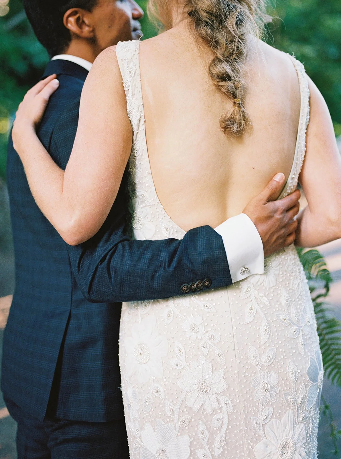 Close-up of the groom’s hand around the bride’s waist, showing the beaded detail of her gown.